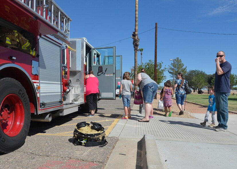 Attendees wait in line to view the fire truck during the Luke's Day for Kids event at Luke Air Force Base, Arizona, Sept. 19, 2015. The 56th Civil Engineer Squadron fire department and Glendale Police department displayed several pieces of equipment they use daily to fight fires and keep the community safe. (U.S. Air Force photo by Senior Airman Devante Williams)