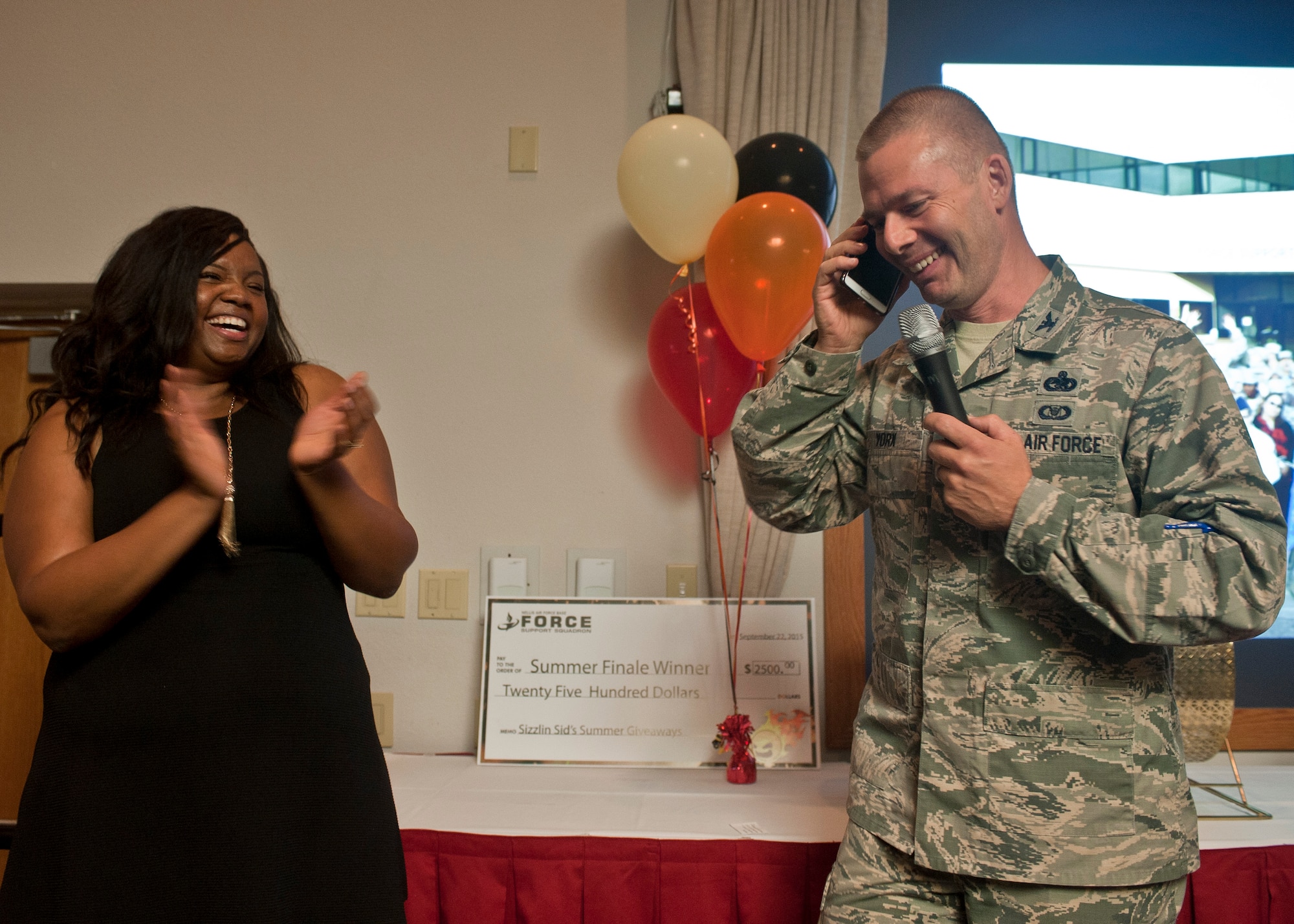 Col. Zev York (right), 99th Air Base Wing vice commander, and Takeira Jones-Bolden, 99th Force Support Squadron supervisory marketing specialist and commercial sponsorship coordinator, laugh while talking to Carlos Del Valle, 99th FSS Outdoor Recreation Center outdoor adventure programmer, to notify him that he had just won the 99th FSS’ Ultimate Summer Giveaway grand prize of a brand new 2015 Volkswagen Jetta at Nellis Air Force Base, Nev., Sept. 22, 2015. Del Valle has worked at Outdoor Rec since 2010, and plans on driving the new car to work every day. (U.S. Air Force photo by Staff Sgt. Siuta B. Ika)