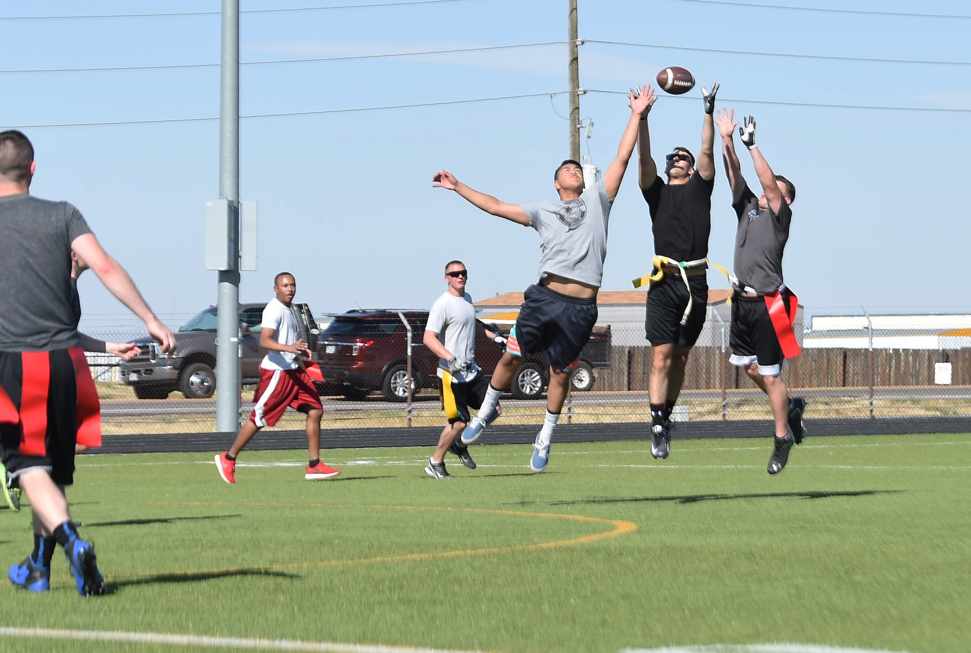 Team Buckley members jump in the air to catch the football during a flag football game Sept. 23, 2015, at the all-purpose field on Buckley Air Force Base, Colo. The game was a chance for junior enlisted members to engage in friendly competition against the Buckley 5/6 Association, while allowing NCOs the opportunity to mentor younger Airmen in a non-professional setting.  (U.S. Air Force photo by Airman 1st Class Samantha Meadors/Released)
