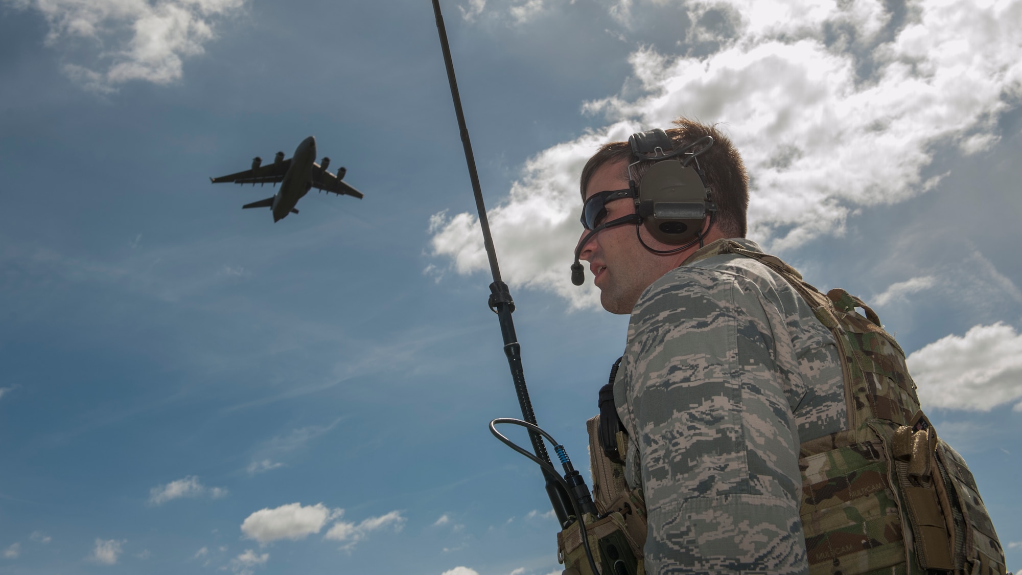 First Lt. Andrew Schnell, 621st Contingency Response Squadron airfields operations officer, communicates via radio to the C-17A Globemaster III flying overhead during a semi-prepared runway operations (SPRO) training mission Sept. 23, 2015, at Fort A.P. Hill, Va. Schnell was responsible for keeping the runway in operating condition and provided the pilots with advisories from the ground so the aircraft could land safely during the training mission. (U.S. Air Force photo/Airman 1st Class Zachary Cacicia)