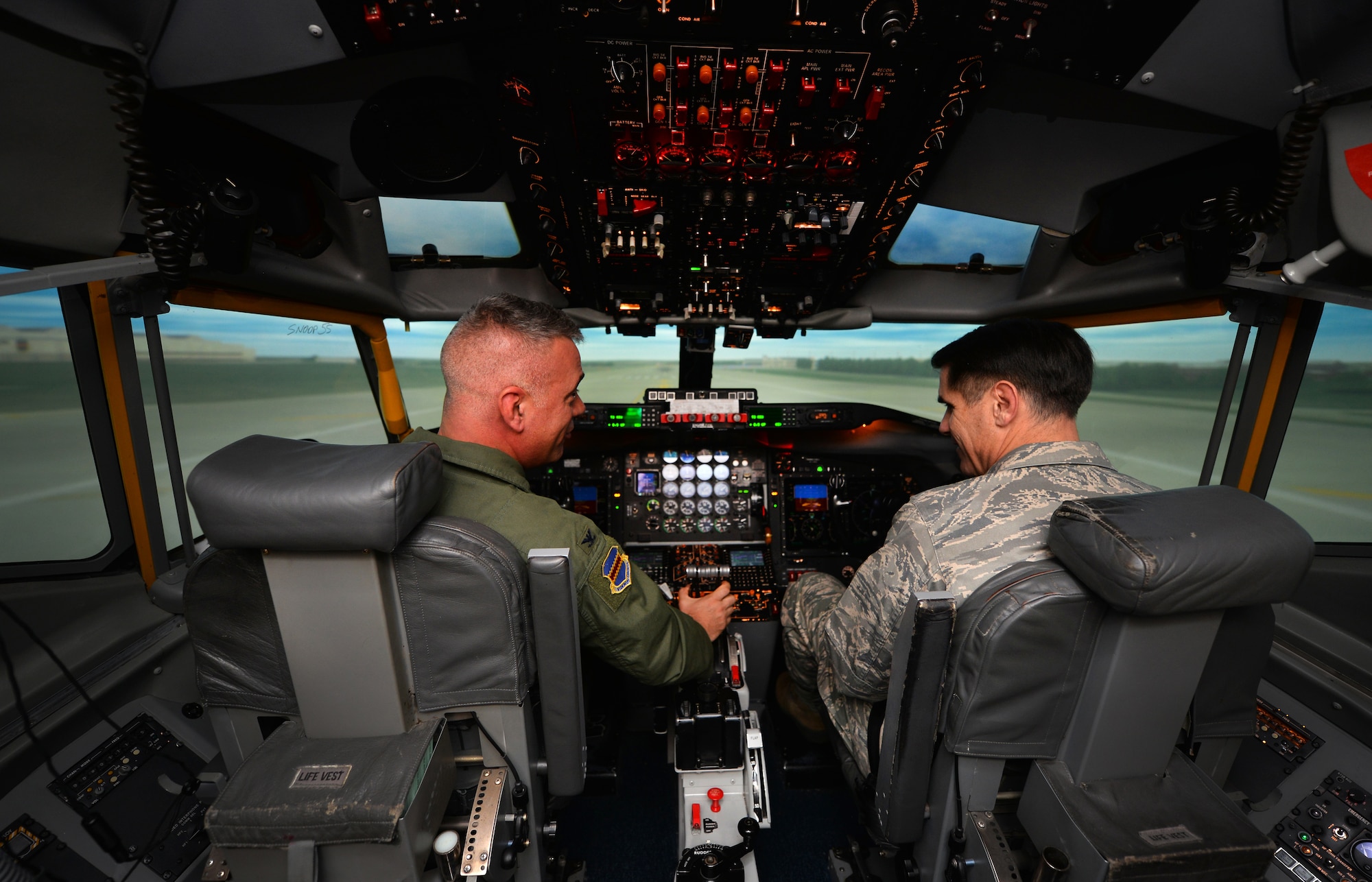 U.S. Air Force Col. Mark Williamson, 55th Wing vice commander, talks with U.S. Air Force Maj. Gen. Bradford Shwedo, 25th Air Force commander, as they take off down a digital runway inside of a flight simulator Sept. 22, Offutt Air Force Base, Neb.  Multiple scenarios and geographic locations can be loaded into the simulator by the navigator in back.  (U.S. Air Force photo / Josh Plueger/released)