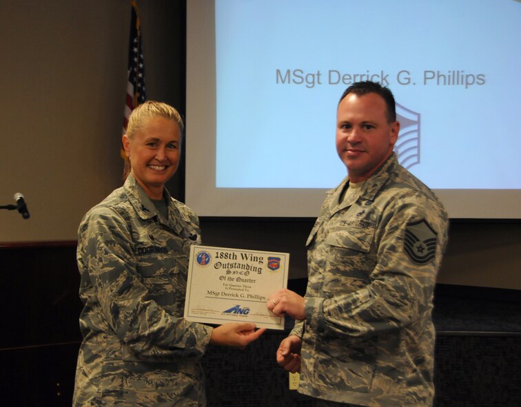 Master Sgt. Derrick Phillips, 153rd Intelligence Squadron, receives the Outstanding Senior Non-Commissioned Officer of the Quarter award Sept. 20, 2015, from Col. Bobbi Doorenbos, 188th Wing commander, at Ebbing Air National Guard Base, Fort Smith, Ark. Phillips distinguished himself by exemplifying leadership and performance skills, self-improvement and physical fitness as well as with base and community involvement. Phillips was presented with a coin and a certificate and will have his portrait displayed in the 188th's Citizen Airman Dining Facility during the next quarter. (U.S. Air National Guard photo by Senior Airman Cody Martin/Released)