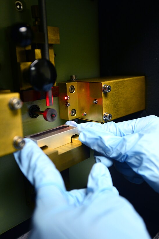 A U.S. Air Force non-destructive inspection apprentice assigned to the 1st Maintenance Squadron inserts a boat into an optical emission spectrometer before analyzing aircraft oil at Langley Air Force Base, Va., Sept 22, 2015. The analysis of aircraft oil by U.S. Service members follows standards set forth by the Joint Oil Analysis Program. (U.S. Air Force photo by Senior Airman Aubrey White/Released)