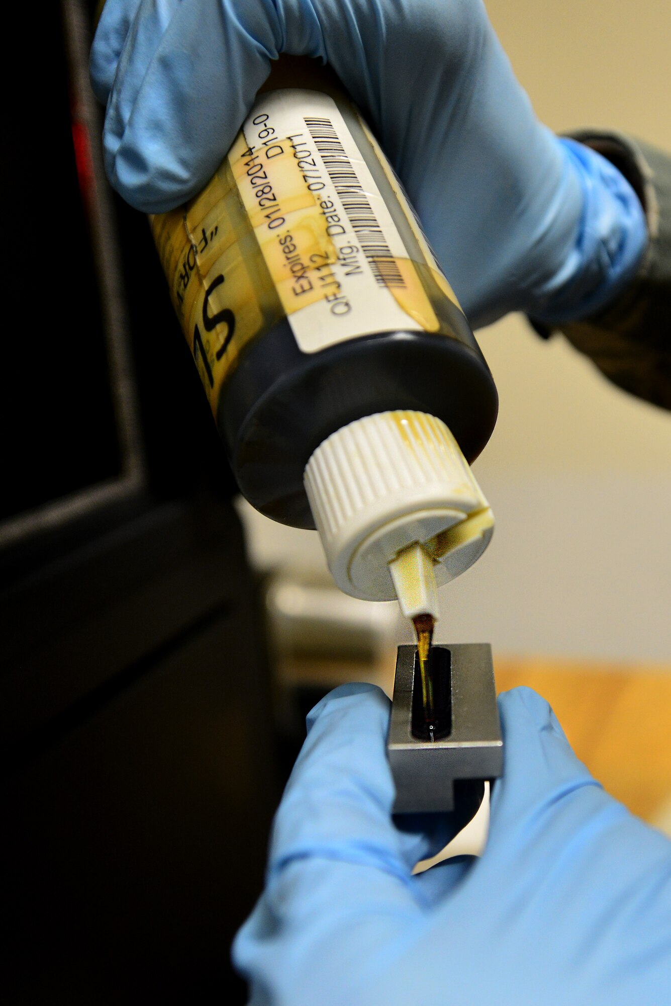 A U.S. Air Force non-destructive inspection apprentice assigned to the 1st Maintenance Squadron pours slop oil into a boat before analyzing the oil at Langley Air Force Base, Va., Sept 22, 2015. After the technician pours the oil into the boat, the boat is inserted into an optical emission spectrometer that will burn the oil to measure the intensity of the light it emits, alluding to the type of particles in the oil. (U.S. Air Force photo by Senior Airman Aubrey White/Released)