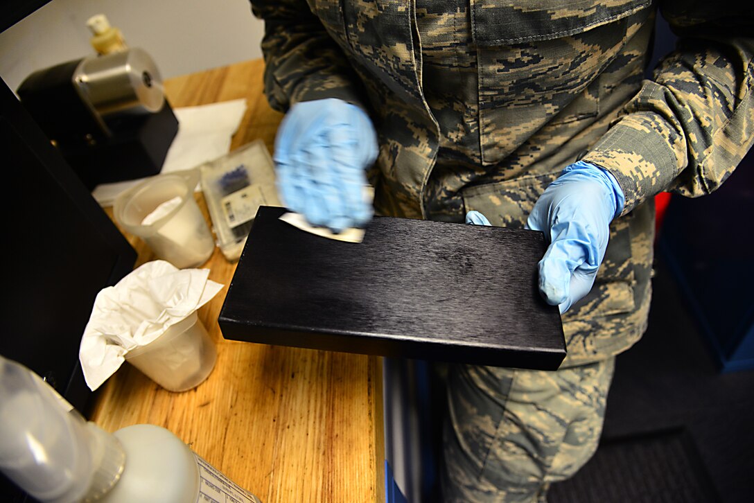 A U.S. Air Force non-destructive inspection apprentice assigned to the 1st Maintenance Squadron cleans an optical emission spectrometer component after analyzing an aircraft oil sample at Langley Air Force Base, Va., Sept. 22, 2015. Cleaning the spectrometer occurs after every five oil burnings to ensure proper analysis of metal fragments. (U.S. Air Force photo by Senior Airman Aubrey White/Released)