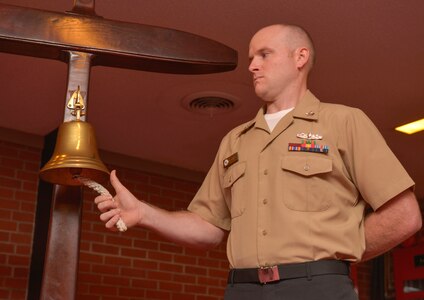 Navy Information Systems Technician, 2nd Class Seth Oswald prepares to ring the bell during the Navy Gold Star remembrance ceremony Sept. 23, 2015at Good Shepherd Chapel on Joint Base Charleston –Weapons Station, Charleston, S.C. The event honors local fallen Sailors. Oswald rang the bell each time one of the deceased Sailor’s names was read.