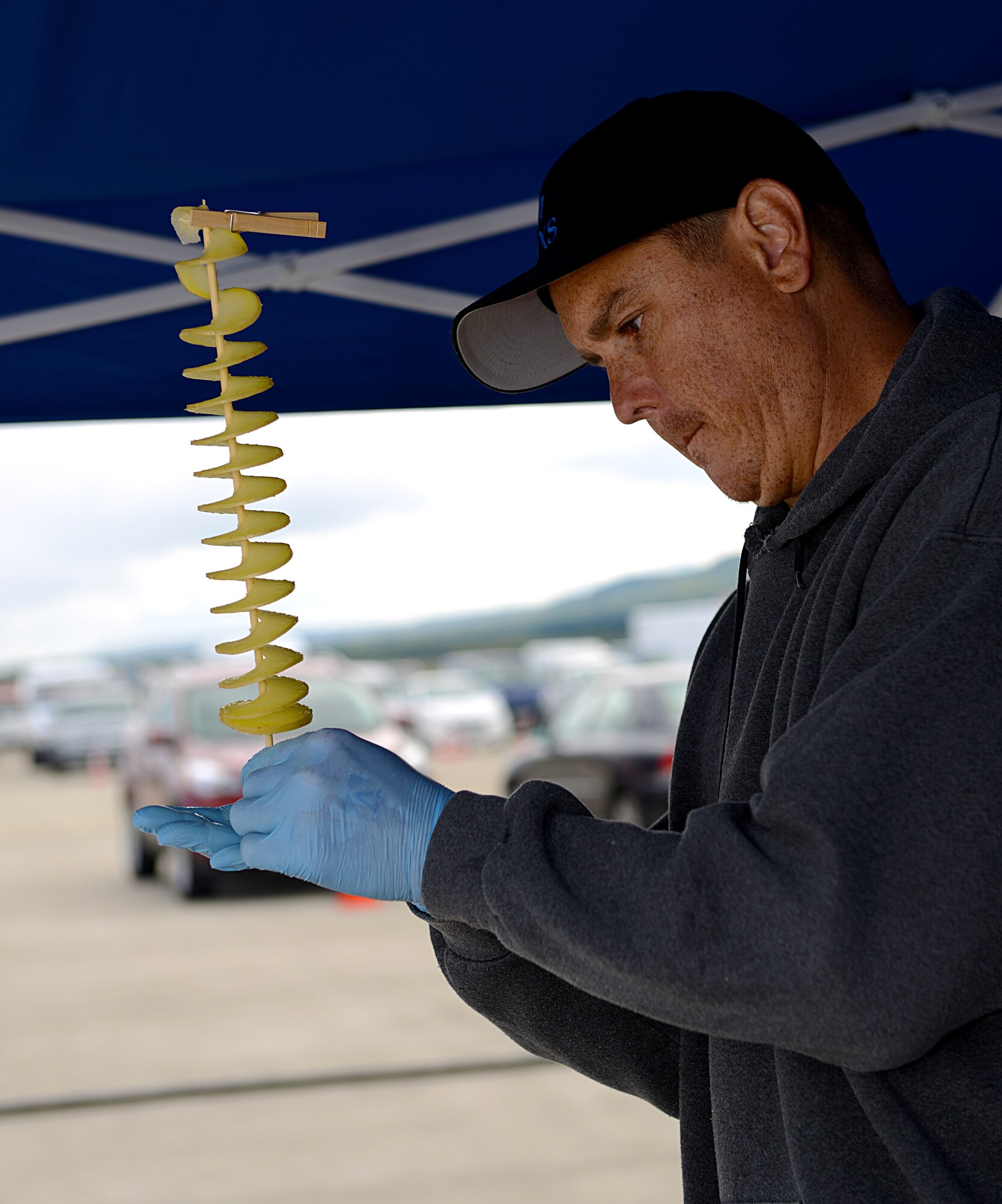 Tech. Sgt. Robert Campbell, 721st Aircraft Maintenance Squadron, prepares a spiral potato for a patron of the 51st Ramstein Bazaar Sept. 19, 2015, at Ramstein Air Base, Germany. Along with German vendors, base organizations and booster clubs were allowed to set up at the bazaar to provide information about their services and sell food items. (U.S. Air Force photo/Senior Airman Timothy Moore)