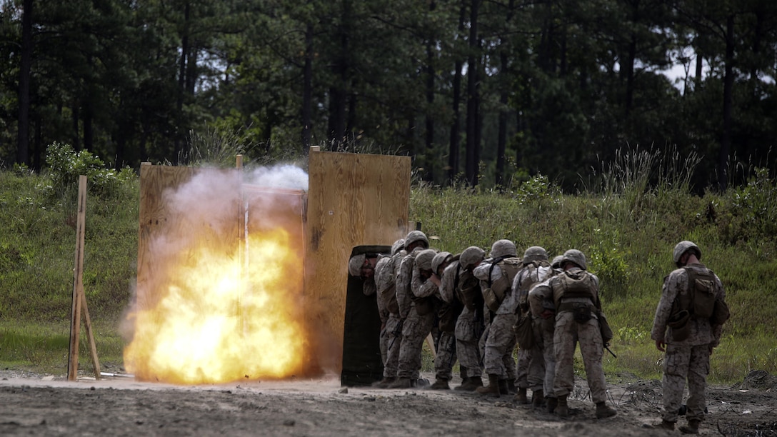 Marines with 2nd Battalion, 2nd Marine Regiment take cover behind a shielding blanket as an urban charge detonates during a demolitions exercise with 2nd Combat Engineer Battalion at Engineer Training Area 7 on Marine Corps Base Camp Lejeune, N.C., Sept. 22, 2015. Marines with 2/2 increased their proficiency and knowledge with various charges and techniques with the help of 2nd CEB.