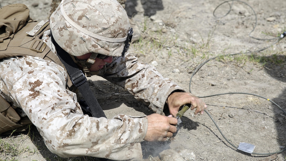 A Marine with 2nd Battalion, 2nd Marine Regiment lays in the prone while he pulls the timed fuse on a Bangalore charge to destroy a wire trap during a demolitions exercise with 2nd Combat Engineer Battalion at Engineer Training Area 7 on Marine Corps Base Camp Lejeune, N.C., Sept. 22, 2015. Marines with 2/2 increased their proficiency and knowledge with various charges and techniques with the help of 2nd CEB.