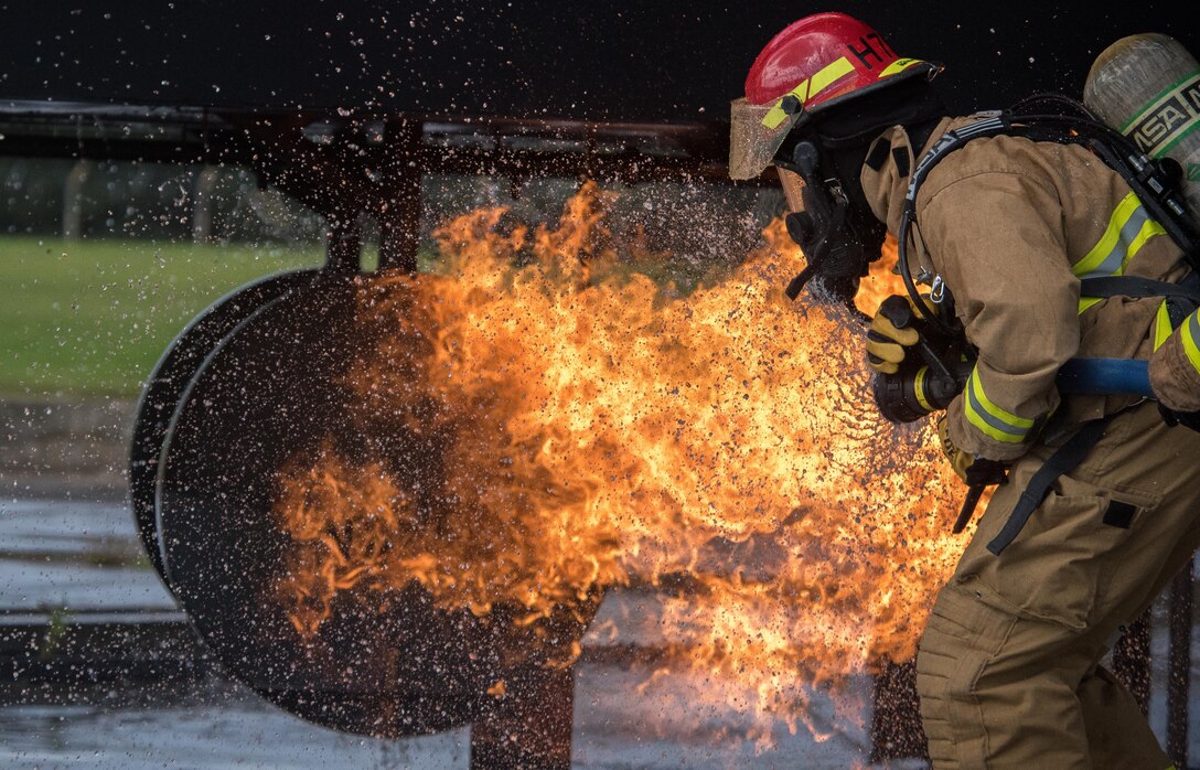 Chief Master Sgt. Vincent Marler, the 48th Fighter Wing command chief, sprays a mock F-15 fighter jet with water during live-fire training at the burn pit on Royal Air Force Lakenheath, England, Sept. 17, 2015. Marler joined the 48th Civil Engineer Squadron Fire Department training to understand the skills and techniques required to effectively put out an aircraft fire. (U.S. Air Force photo/Senior Airman Trevor T. McBride)
