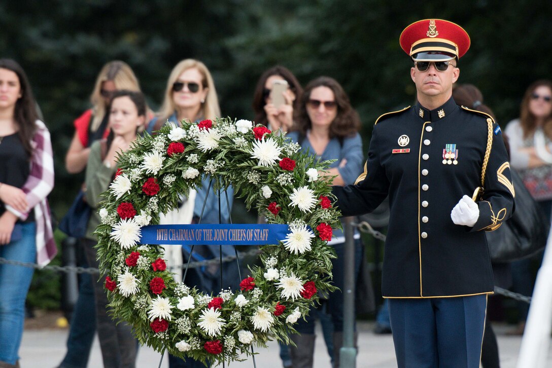 A soldier stands by a wreath at the Tomb of the Unknown Soldier at Arlington National Cemetery in Arlington, Va., Sept. 25, 2015. Army Gen. Martin E. Dempsey, chairman of the Joint Chiefs of Staff, placed the wreath to honor unknown service members as he prepared to retire after 41 years of service. U.S. Army photo by Spc. Cody W. Torkelson