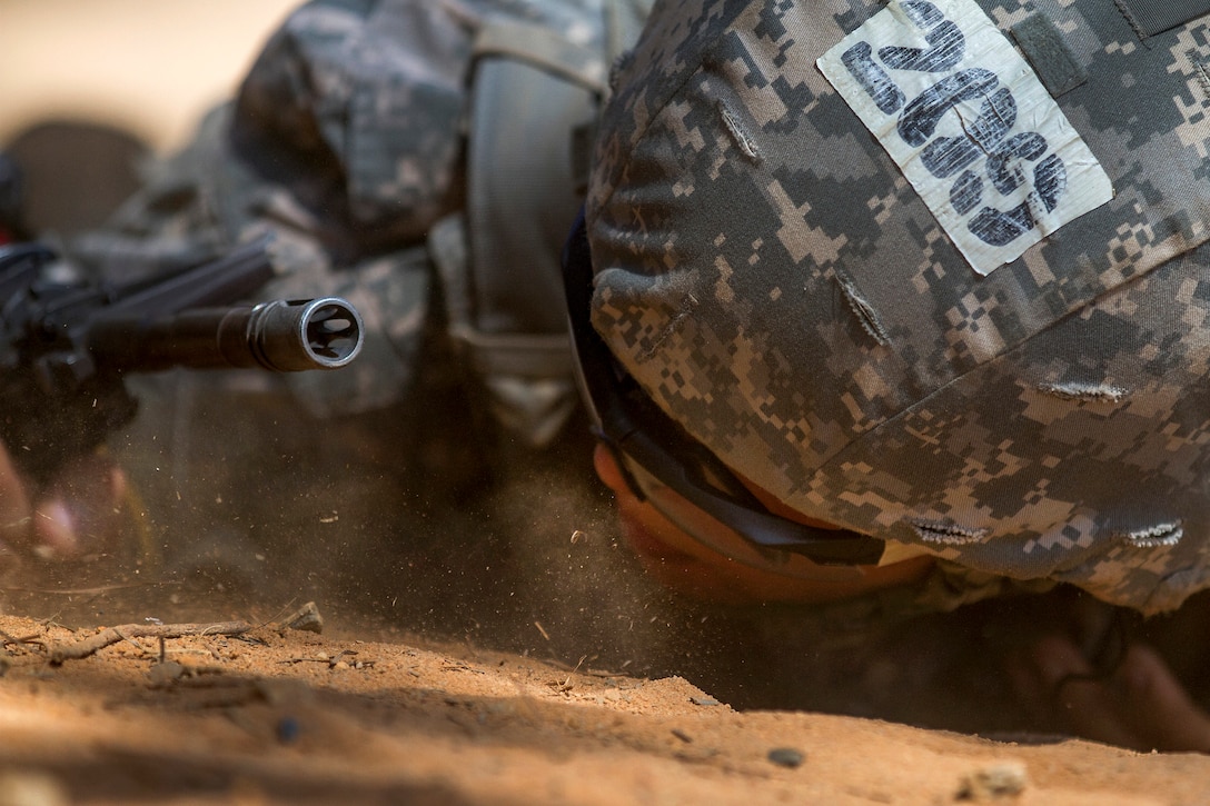 A soldier low crawls through an obstacle on a buddy team live-fire lane during basic training on Fort Jackson, S.C., Sept. 19, 2015. U.S. Army photo by Sgt. Ken Scar
