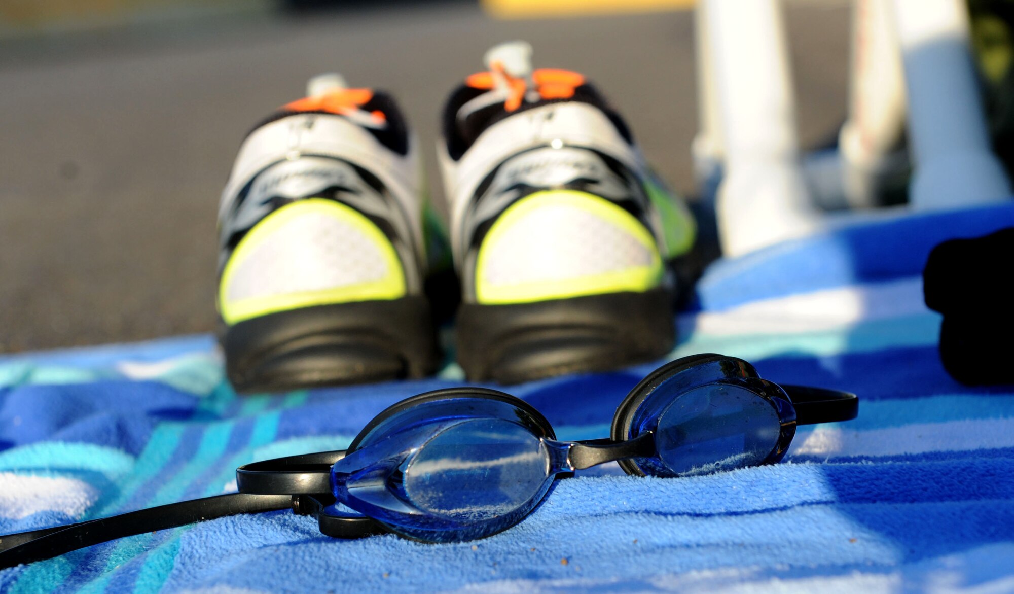 A pair of swimming goggles and tennis shoes sit on a towel during Keesler’s mini-triathlon Sept. 25, 2015, Keesler Air Force Base, Miss. The event included a 200-yard swim, 9-mile bike ride and a 2-mile run. (U.S. Air Force photo by Kemberly Groue)