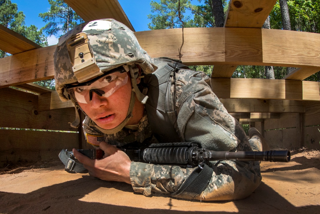 Army Pvt. Joshua Finau crawls under an obstacle on the live-fire buddy lane during training at Fort Jackson, S.C., Sept. 19, 2015. U.S. Army photo by Sgt. Ken Scar