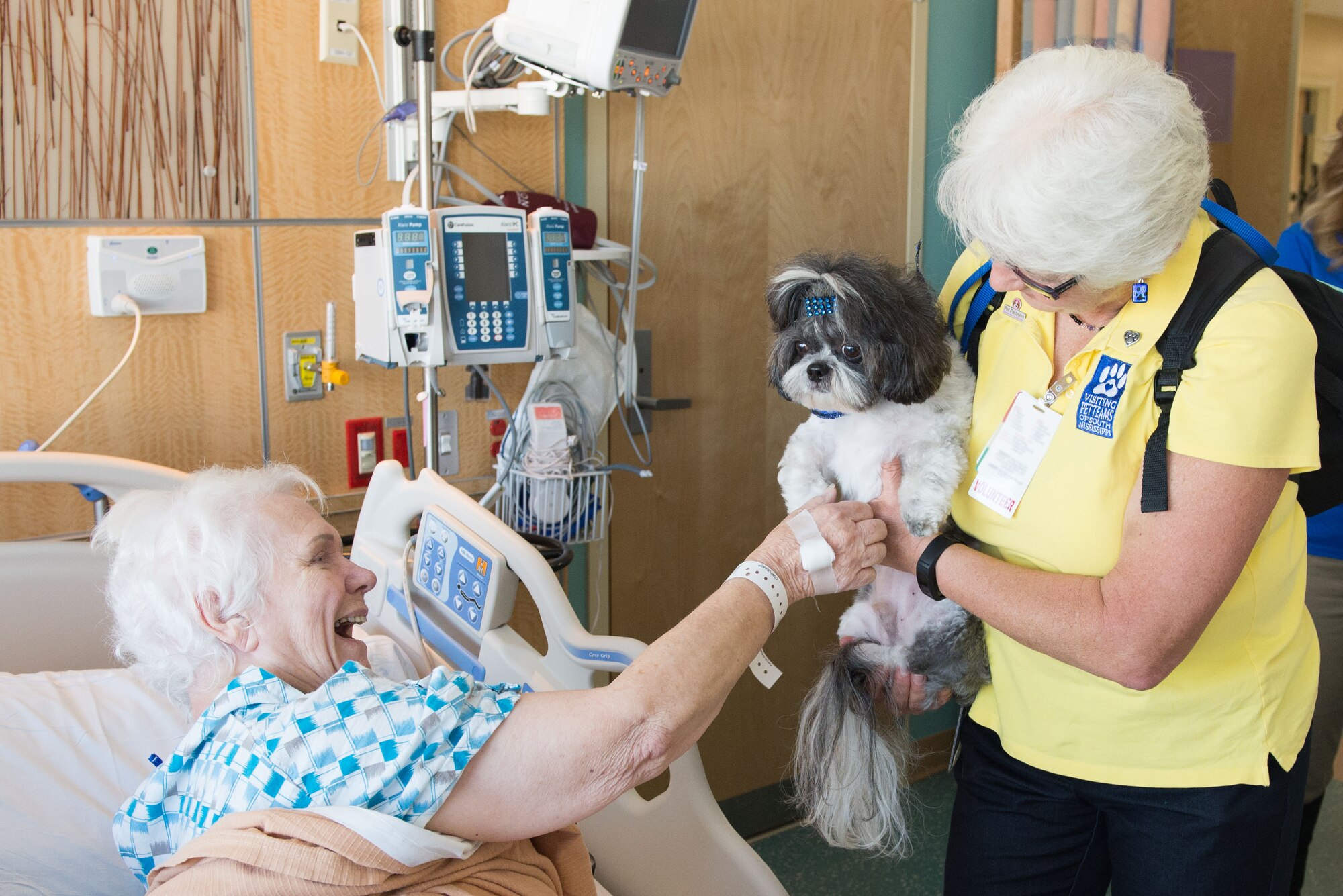 Sue Reiter, Surgical Inpatient Unit patient, receives a visit from Jan Tucker, Visiting Pet Teams of South Mississippi volunteer, and her dog, Toby, a People Utilizing Pet Services program therapy dog, during the first PUPS program visit at the Keesler Medical Center Sept. 24, 2015, Keesler Air Force Base, Miss. The program allows dogs that are certified through the Delta Society, based in Gulfport, Miss, to visit patients at the medical center.  (U.S. Air Force photo by Marie Floyd)