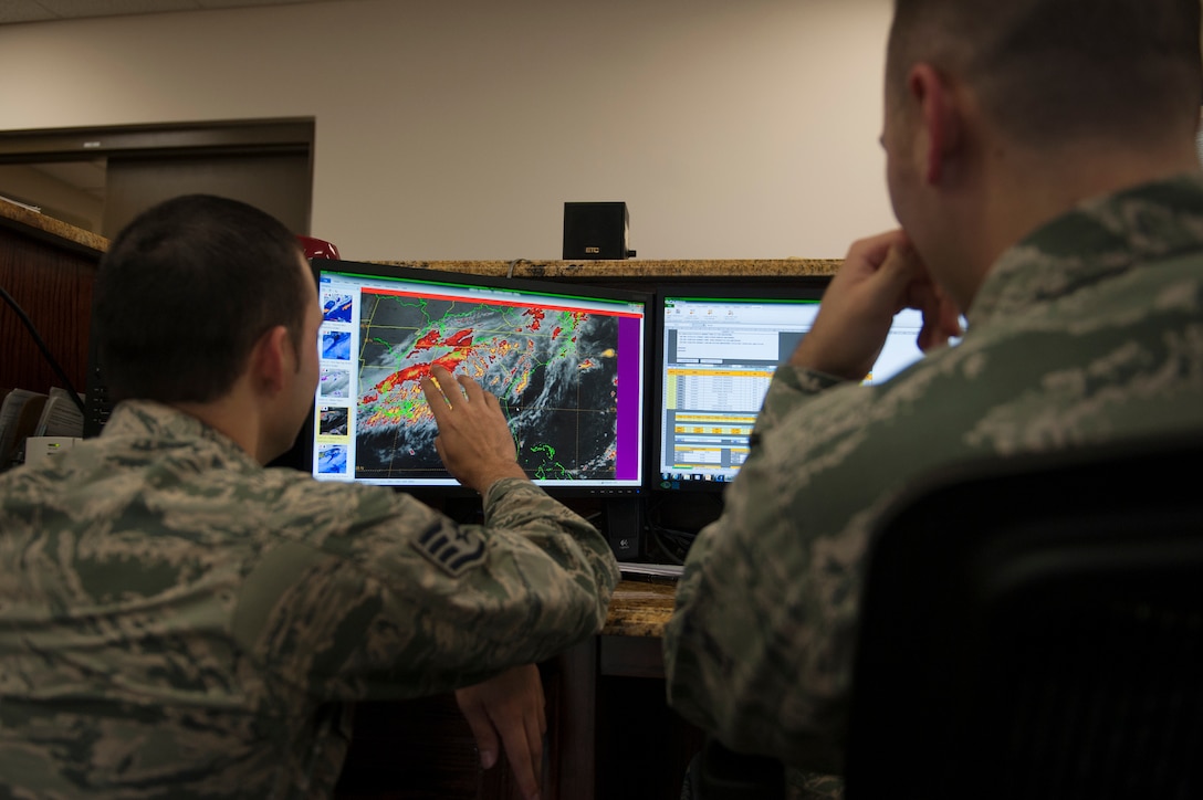U.S. Air Force Staff Sgt. Mark Bratic, left, 23d Operations Support Squadron NCO in charge of airfield weather, briefs Airman 1st Class Lucas Payne, 23d OSS weather technician during a shift change Sept. 21, 2015, at Moody Air Force Base, Ga. Forecasters conduct these briefs to incoming shift members to inform them of what the weather forecast status in the last eight hours and what is expected to happen in the next 24 hours. (U.S. Air Force photo by Airman 1st Class Kathleen D. Bryant/Released)
