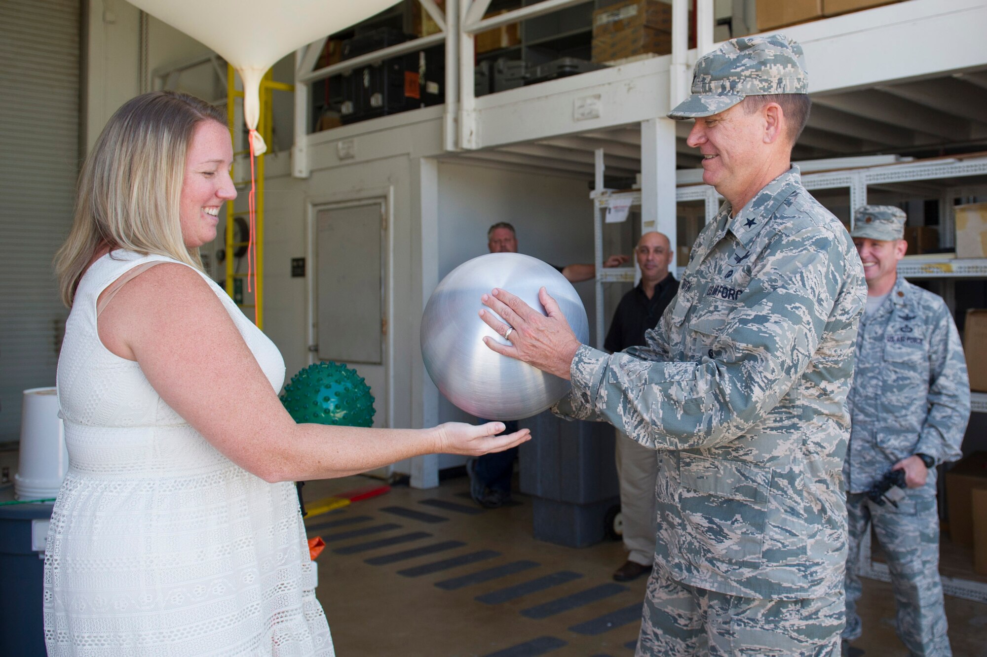 Suzanne Siverling, 45th Weather Squadron, hands Brig. Gen. Wayne Monteith, 45th Space Wing commander, a 12-inch sphere used for radar calibration Sept. 22 at Cape Canaveral Air Force Station, Florida. The wing commander met with the personnel from 45th OG and was introduced to the facilities they use in daily operations. (U.S. Air Force photo by Matthew Jurgens/Released)