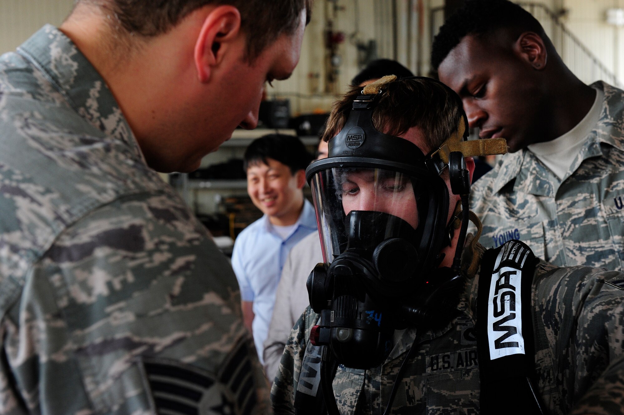 Staff Sgt. Ian Coye, 8th Civil Engineer Squadron firefighter crew chief, and Airman 1st Class Boston Young, 8th CES firefighter, help Airman 1st Class Ronald Carv, 8th CES firefighter, as he prepares to put on a bio suit as part of a demonstration at Kunsan Air Base, Republic of Korea, Sept. 16, 2015. In addition to the demonstration, the Gunsan City fire department received a tour of the station and engaged the Airmen to ask questions. (U.S. Air Force photo by Staff Sgt. Nick Wilson/Released)