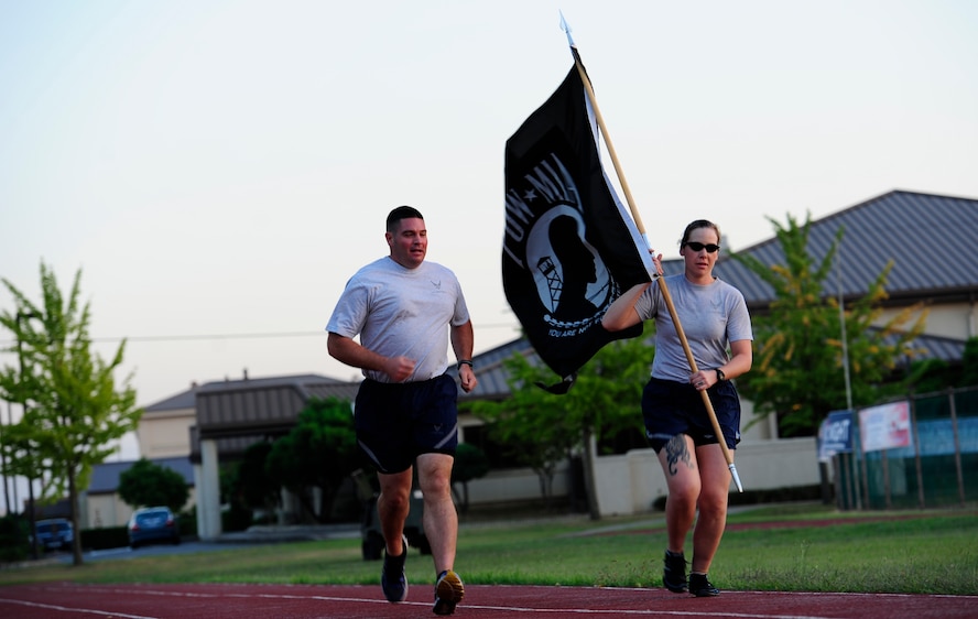 Master Sgt. Eric Sisson, 35th Aircraft Maintenance Unit Panton weapon section chief, runs with Tech. Sgt. Rebecca Edwards, 8th Fighter Wing command chief assistant, Sept. 17, 2015. The Wolf Pack community volunteered to take turns carrying the Prisoner of War/Missing in Action flag during the run and to read aloud names at the vigil non-stop for 24 hours. (U.S. Air Force photo by Staff Sgt. Nick Wilson/Released)