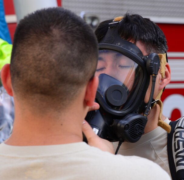 An Airman assigned to the 51st Civil Engineer Squadron's emergency management response team assists Staff Sgt. Jeffrey Williams, 51 CES emergency management plans and programs, with removing his respirator Sept. 24, 2015, near the city of Songtan, Republic of Korea. Airmen took advantage of a unique training opportunity to train in a simulated hazardous materials environment. (U.S. Air Force photo by Staff Sgt. Benjamin Sutton)