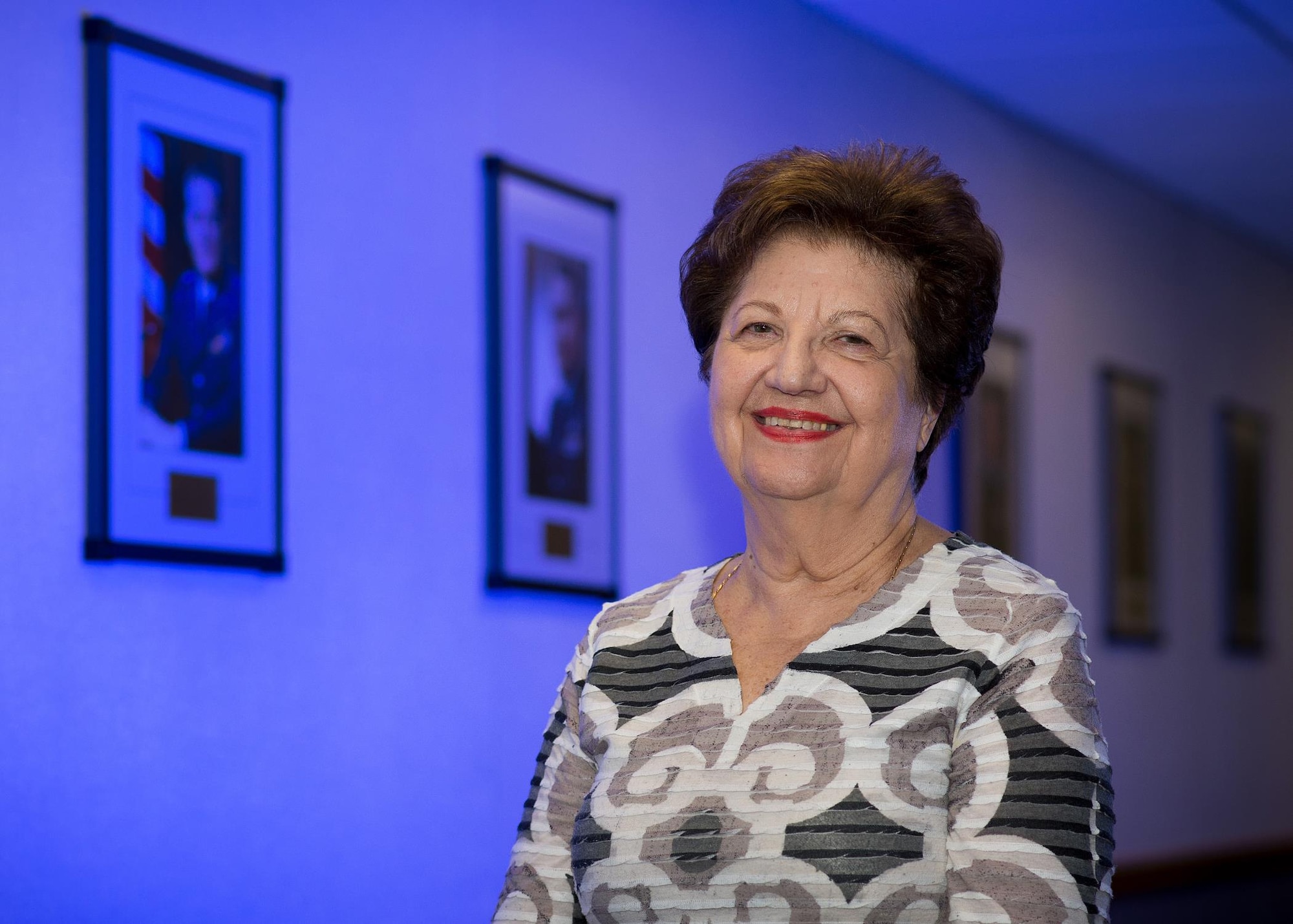 Maria Bandouveres, the executive assistant to the C3I and Networks program executive officer, stands alongside the portraits of all 19 Electronic Systems Division and Electronic Systems Center commanders at Hanscom Air Force Base, Mass., Sept. 15, 2015. Bandouveres, who has been a civil service employee since June 1944, has worked on the command staff for 17 of thoe 19 commanders. (U.S. Air Force photo/Mark Herlihy)