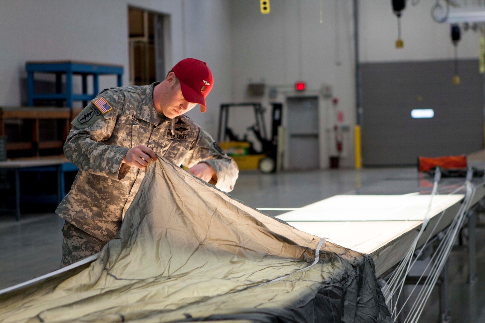 Army Staff Sgt. David Lewis inspects the canopy of a parachute before packing it for use. Lewis is an airborne rigger with DLA Distribution Susquehanna, Pa.
