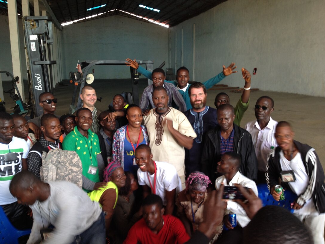 Jason Zeppuhar, second row from back, second from right, pose with other members of the DLA Distribution Expeditionary Team and locals from the area during a party before the team departed Liberia.