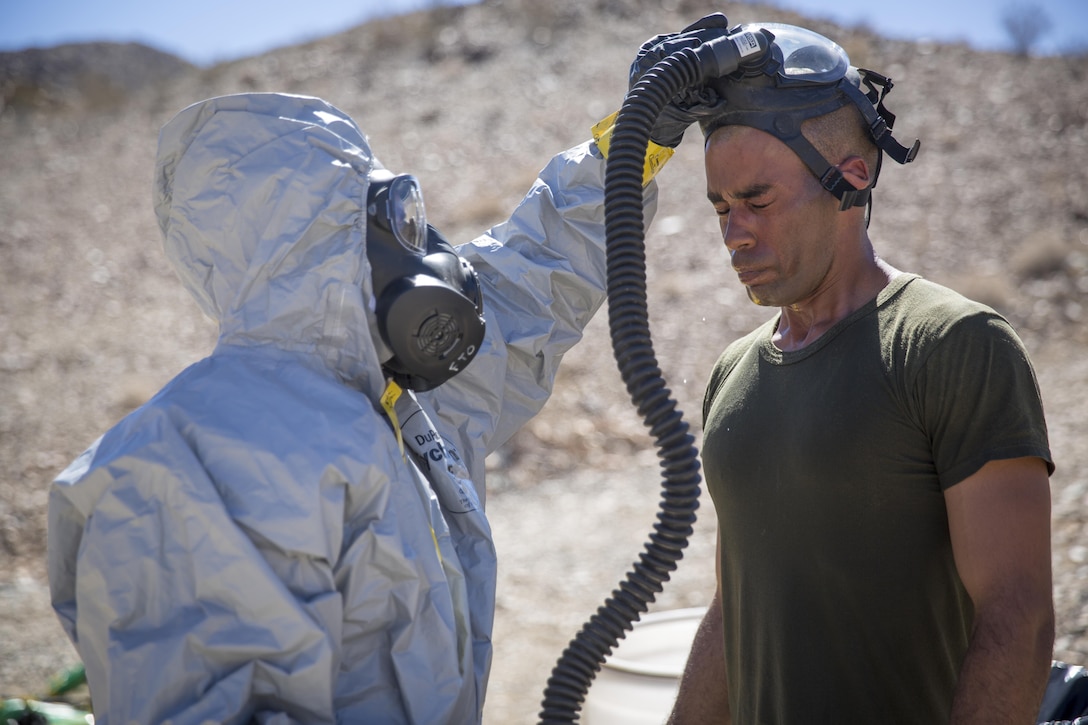 Marine Corps Sgt. Mitchell D. Taylor receives assistance with removing his mask after undergoing a decontamination process during a simulated chemical ordnance hazard removal exercise at the Marine Corps Air Ground Combat Center in Twentynine Palms, Calif., Sept. 20, 2015. Taylor is an explosive ordnance disposal technician with the 3rd Explosive Ordnance Disposal Unit, 9th Engineer Support Battalion. Marine Corps photo by Lance Cpl. Levi Schultz