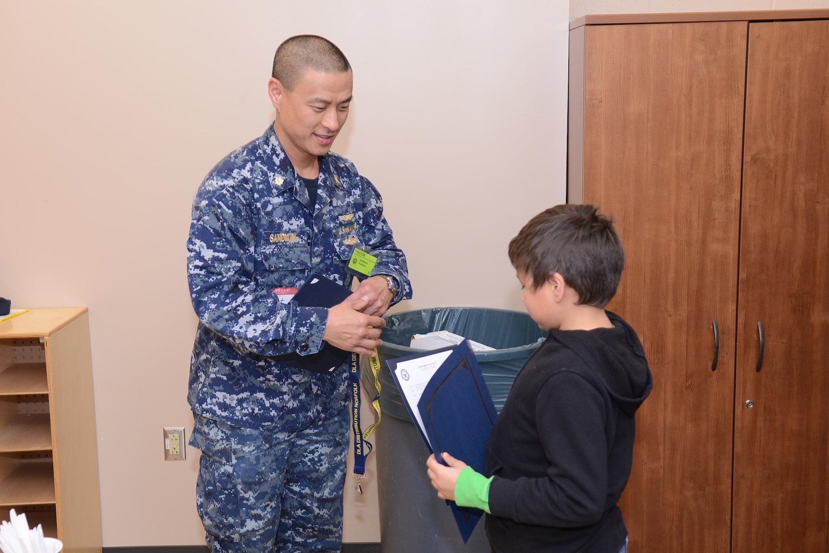 Navy Lt. Cmdr. Brett Sandman, assistant site director of DLA Distribution Norfolk, Va., at New London, Conn., presents a certificate to a Northeast Academy student during the recent Groton ROCKS program.