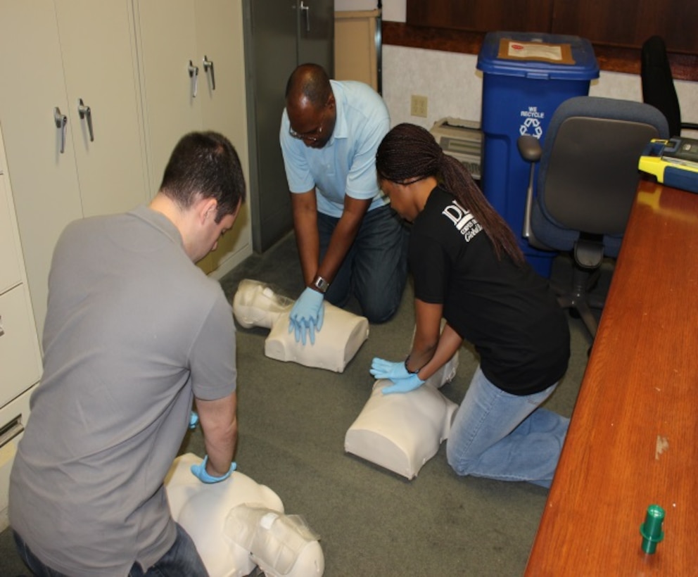 DLA Distribution Corpus Christi, Texas, employees, from top, clockwise, Brian Miller, Samantha Bailey, and Reginald Evans, practice cardiopulmonary resuscitation on mannequins during a class practical exercise.