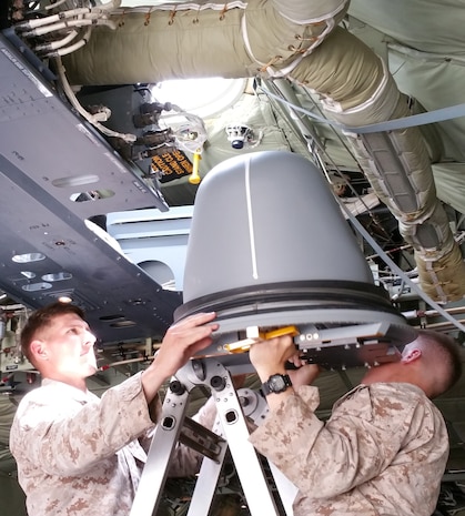 Marines muscle the Hatch-Mounted Satellite Communication Antenna System into the hatch of a C-130 Hercules aircraft. HMSAS provides secure voice, tactical classified network access, common tactical picture, secure chat and streaming intelligence and reconnaissance video for commanders in the field. 
