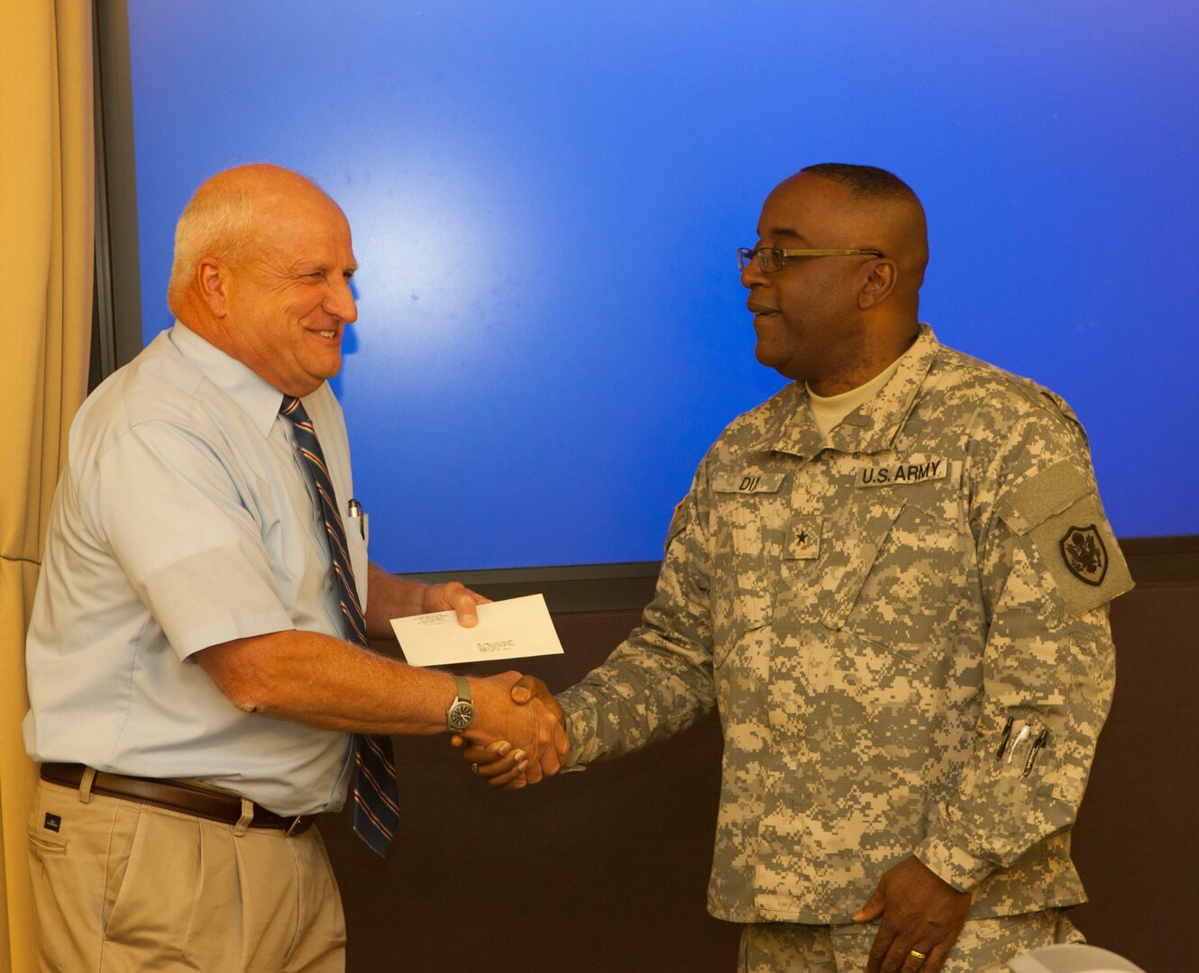 DLA Distribution commander Brig. Gen. Richard Dix presents ALU course instructor Lee Holland with a coin for his years of support towards America’s logisticians.