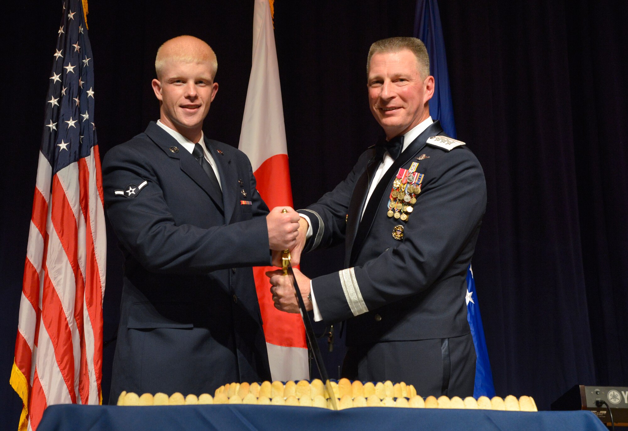 Airman Spencer Patton, 374th Civil Engineer Squadron emergency management apprentice, Lt. Gen. John Dolan, U.S. Forces Japan and 5th Air Force commander, cut the cake as part of the opening ceremony of the Air Force ball at Yokota Air Base, Japan, Sept. 25, 2015. As part of the ball’s opening ceremony, it’s tradition for the most senior and junior Airmen to cut the cake. (U.S. Air Force photo by Senior Airman David Owsianka/Released)