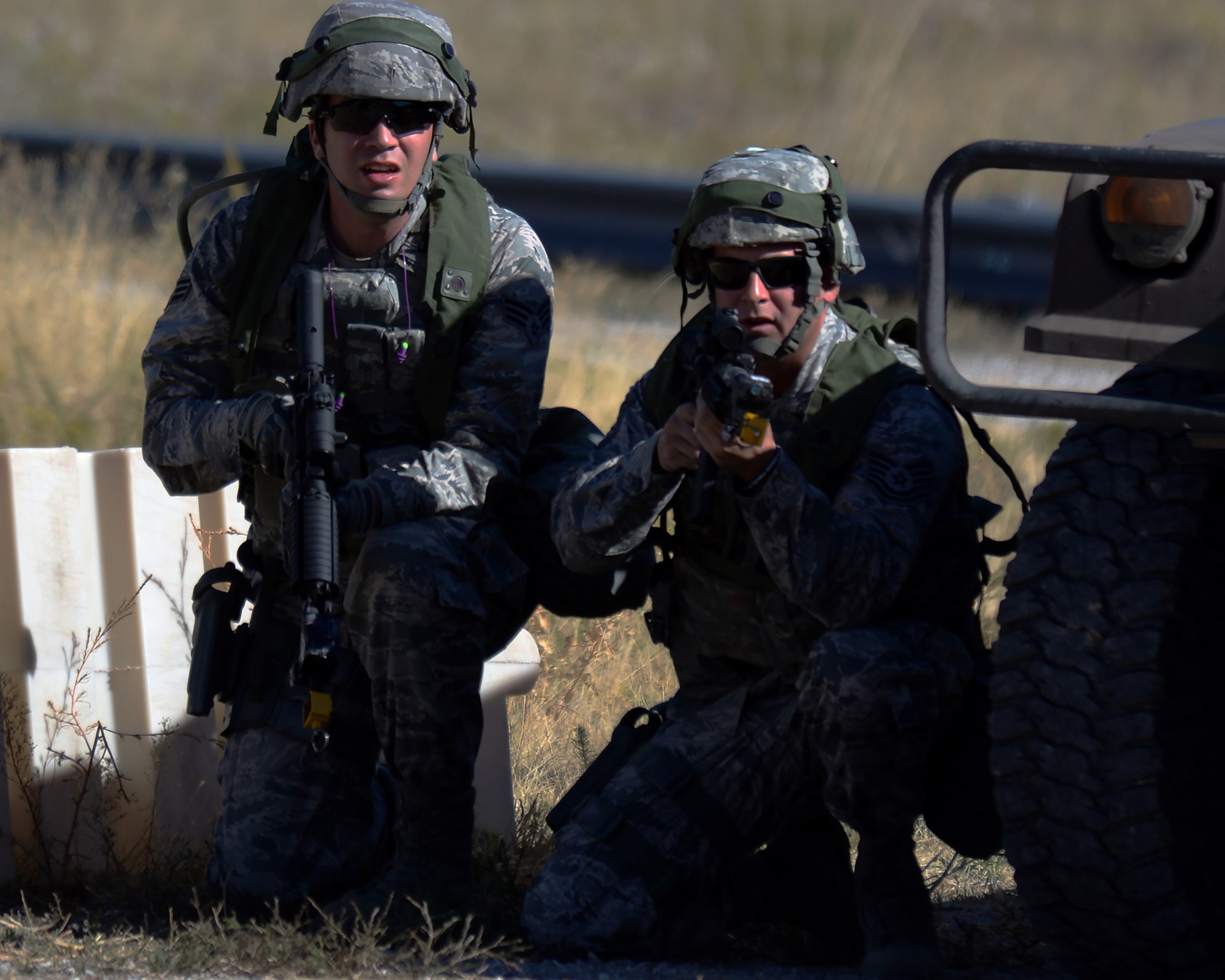 Senior Airman Chaz Thomas and Staff Sgt. Paul Downs, 307th Bomb Wing, Barksdale Air Force Base, La., use a Humvee for cover as they survey the area Sept. 24, 2015, during the tactical recapture portion of the 2015 Global Strike Challenge security forces competition at Camp Guernsey, Wyo. Teams had to search through a village for an asset that was stolen by opposing forces. (U.S. Air Force photo by Senior Airman Brandon Valle)
