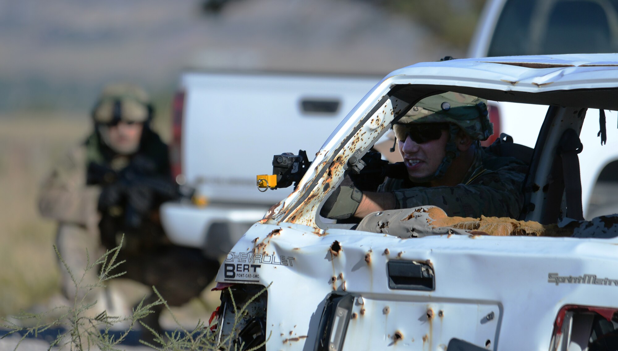 Senior Airman Brandon Weese, 91st Missile Squadron, Minot Air Force Base, N.D., uses a car for cover while Staff Sgt. Jesse Koritar, 91st MW, prepares to move to a different cover during the tactical recapture portion of the 2015 Global Strike Challenge security forces competition on Camp Guernsey, Wyo., Sept. 24, 2015. Each five-man team had to work together to infiltrate a town and recapture a missing asset while opposing forces worked to stop them. (U.S. Air Force photo by Senior Airman Brandon Valle)