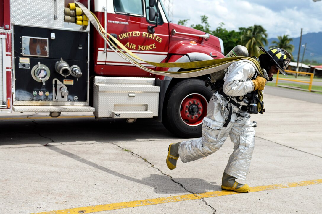 Senior Airman Darius Kirk, a 612th Air Base Squadron firefighter, runs a hose from a fire truck during an exercise Sept. 23, 2015, at Soto Cano Air Base, Honduras. Kirk maintains mission readiness during down time by performing exercises and keeping current on training requirements. (U.S. Air Force photo by Staff Sgt. Jessica Condit)