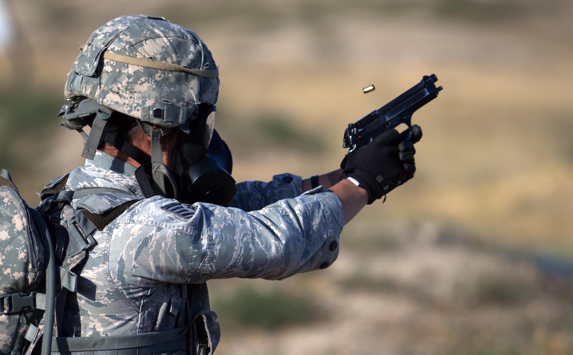 Staff Sgt. Madeline Kappes, 377th Air Base Wing, Kirtland Air Force Base, N.M., shoots at a target with an M-9 pistol while wearing a gas mask Sept. 22, 2015, during the shooting range portion of the 2015 Global Strike Challenge security forces competition on Camp Guernsey, Wyo. Airmen had to be able put on a gas mask at any time during the competition and still perform all of the requested duties. (U.S. Air Force photo by Senior Airman Brandon Valle)