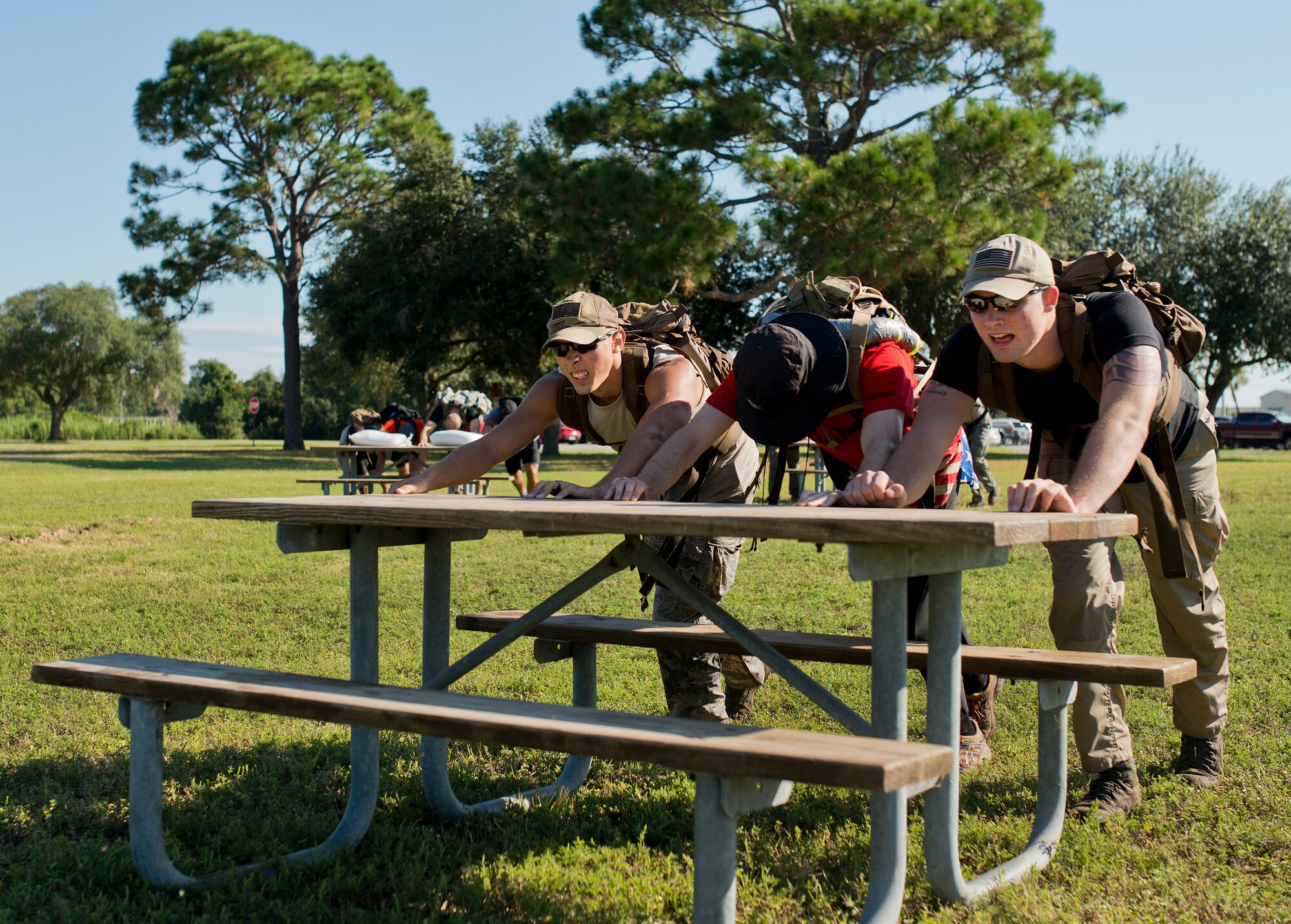 Participants push a picnic table across the grass to simulate plowing a field during the GoRuck team building challenge Sept. 24 at Eglin Air Force Base, Fla.  More than 45 participants pushed themselves through the physical scenarios led by a Special Forces veteran, to earn the blue and black “GoRuck” patch.  (U.S. Air Force photo/Samuel King Jr.)