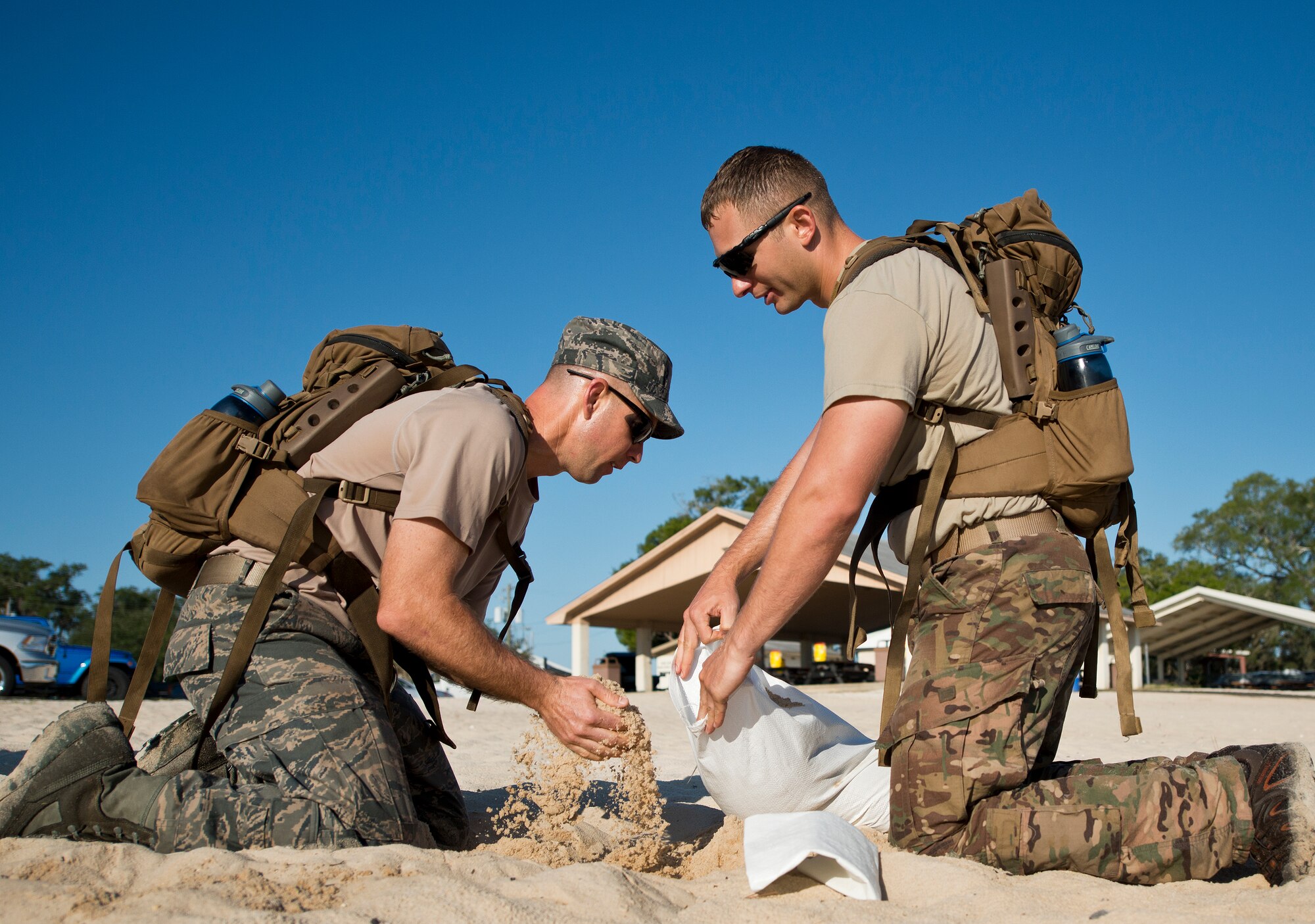 Senior Airman Ben Lackey helps Staff Sgt. Brian Meyer, 366th Training Squadron Det. 3, fill up a sandbag at the beginning of the GoRuck team building challenge Sept. 24 at Eglin Air Force Base, Fla.  More than 45 participants pushed themselves through the physical scenarios led by a Special Forces veteran, to earn the blue and black “GoRuck” patch.  (U.S. Air Force photo/Samuel King Jr.)