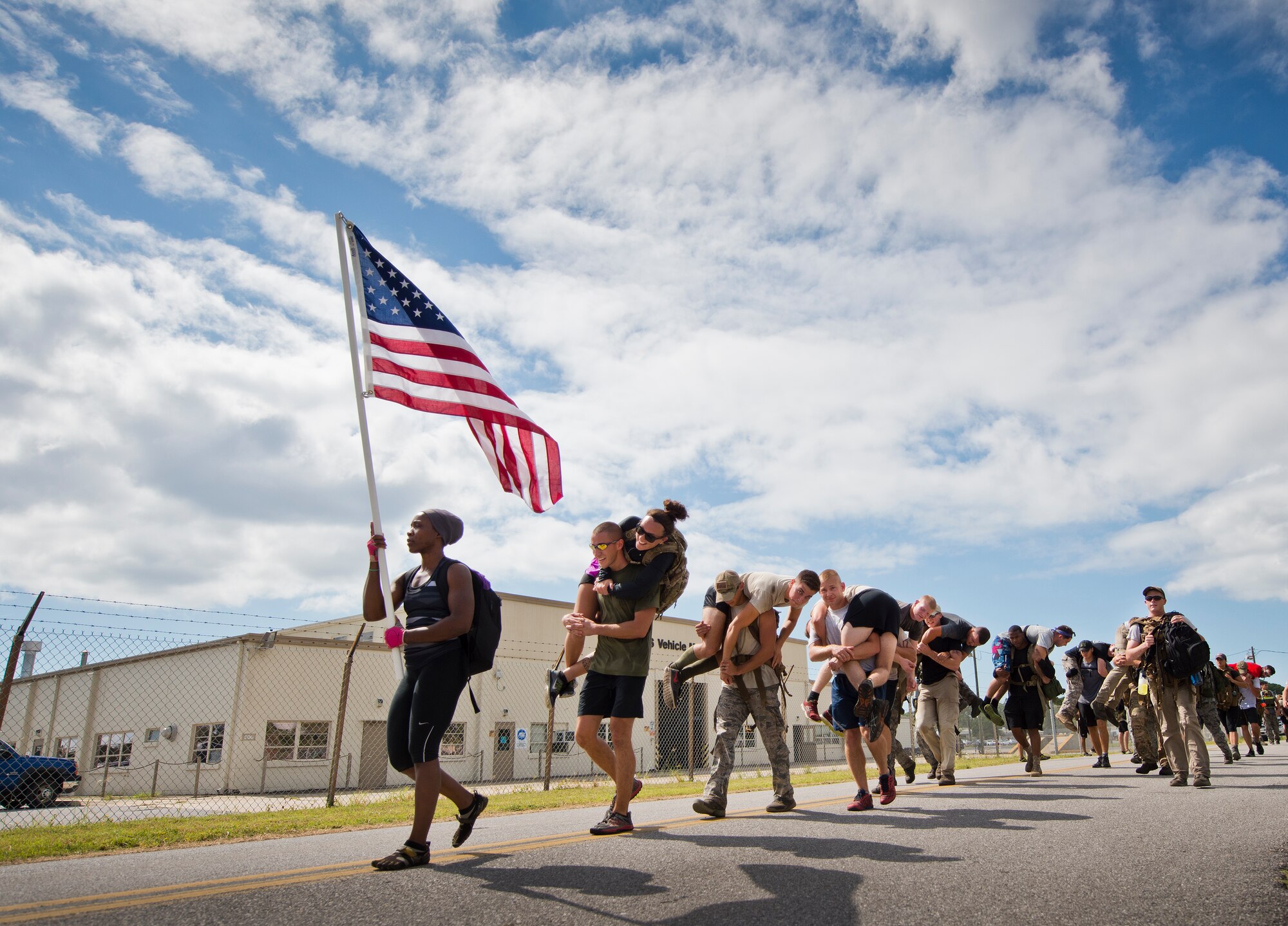 Participants march past vehicle maintenance carrying simulated wounded Sept. 24 at the GoRuck team building challenge at Eglin Air Force Base, Fla.  More than 45 participants pushed themselves through the physical scenarios led by a Special Forces veteran, to earn the blue and black “GoRuck” patch.  (U.S. Air Force photo/Samuel King Jr.)