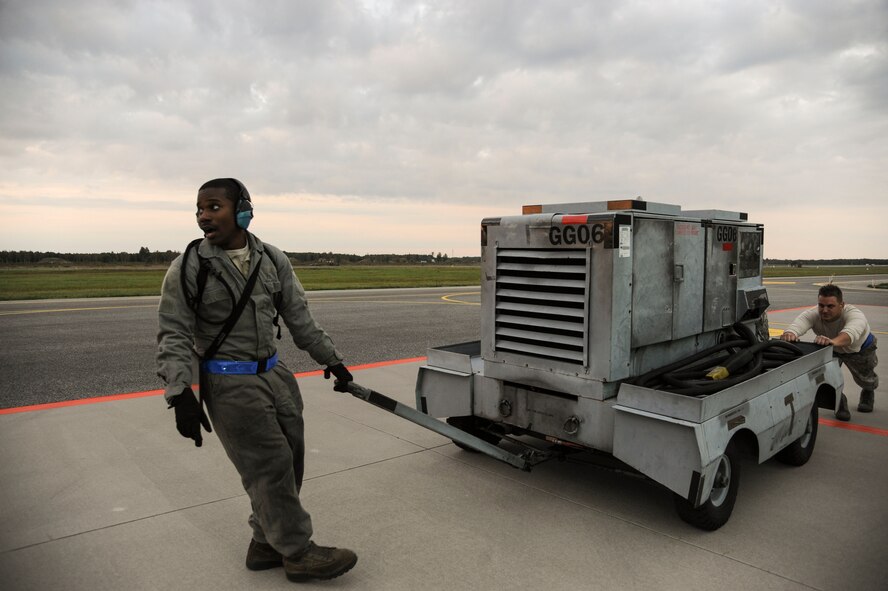 Senior Airman Tayrell Washington, 74th Expeditionary Fighter Squadron weapons load crew team member, and Staff Sgt. Dayton Gravlee, 74th EFS weapons load crew team chief, move a power cart down the flightline at Amari Air Base, Estonia, Sept. 23, 2015. Power carts are used by weapons Airmen to preform functional checks on U.S. Air Force A-10 Thunderbolt II attack aircraft weapons systems. (U.S. Air Force photo by Andrea Jenkins/Released)