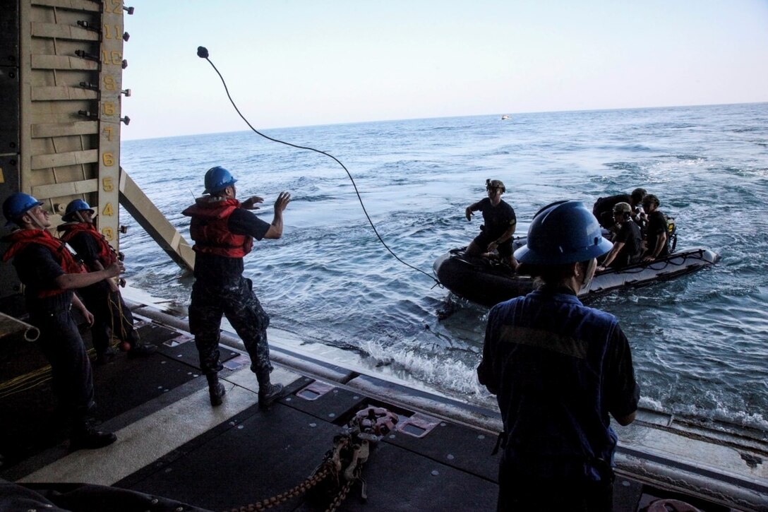 ARABIAN GULF (Sept. 26, 2015) U.S. Marines with the 15th Marine Expeditionary Unit’s Maritime Raid Force throw a rope from their combat rubber raiding craft to Sailors with the Essex Amphibious Ready Group aboard the amphibious assault ship USS Essex (LHD 2). The MRF tested the engines of their CRRC’s in order to maintain combat readiness. The 15th MEU, embarked aboard the ships of the Essex Amphibious Ready Group, is deployed to maintain regional security in the U.S. 5th Fleet area of operations. (U.S. Marine Corps photo by Cpl. Elize McKelvey/Released)