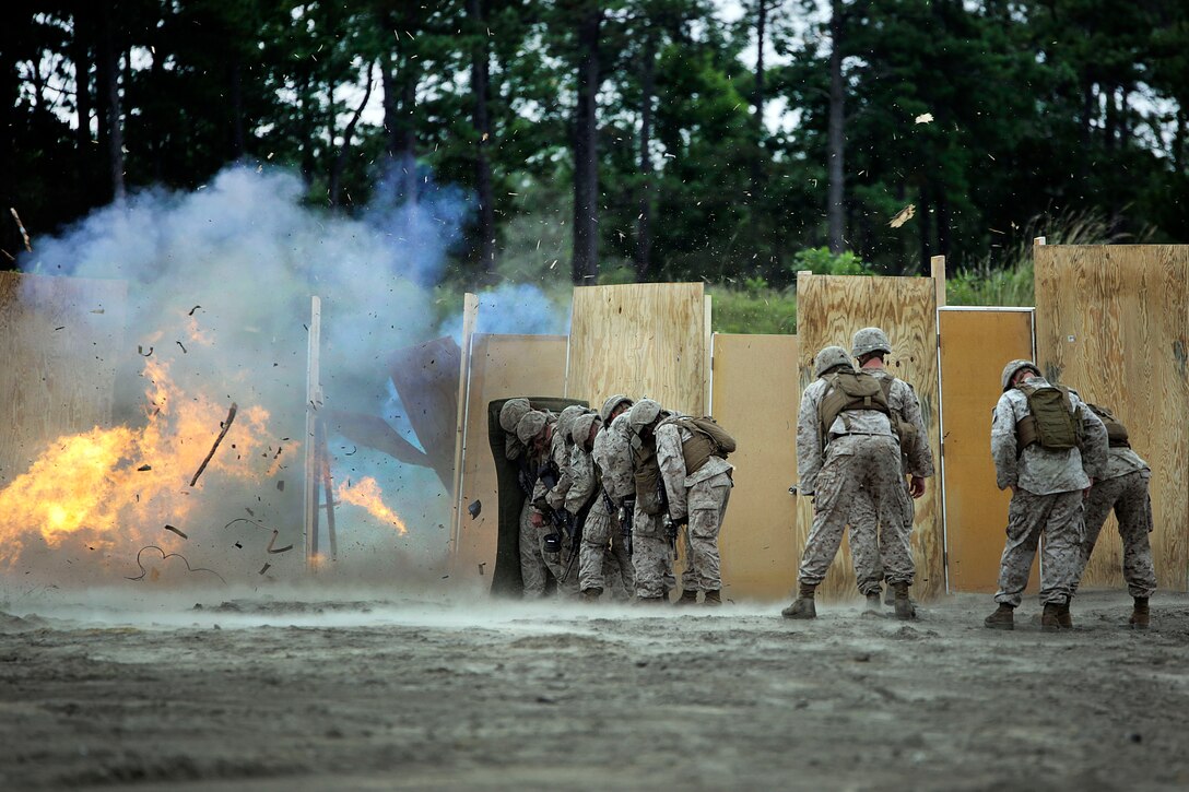 Marines take cover behind a shielding blanket as a charge detonates during a demolitions exercise on Camp Lejeune, N.C., Sept. 22, 2015. U. S. Marine Corps photo by Cpl. Alexander Mitchell