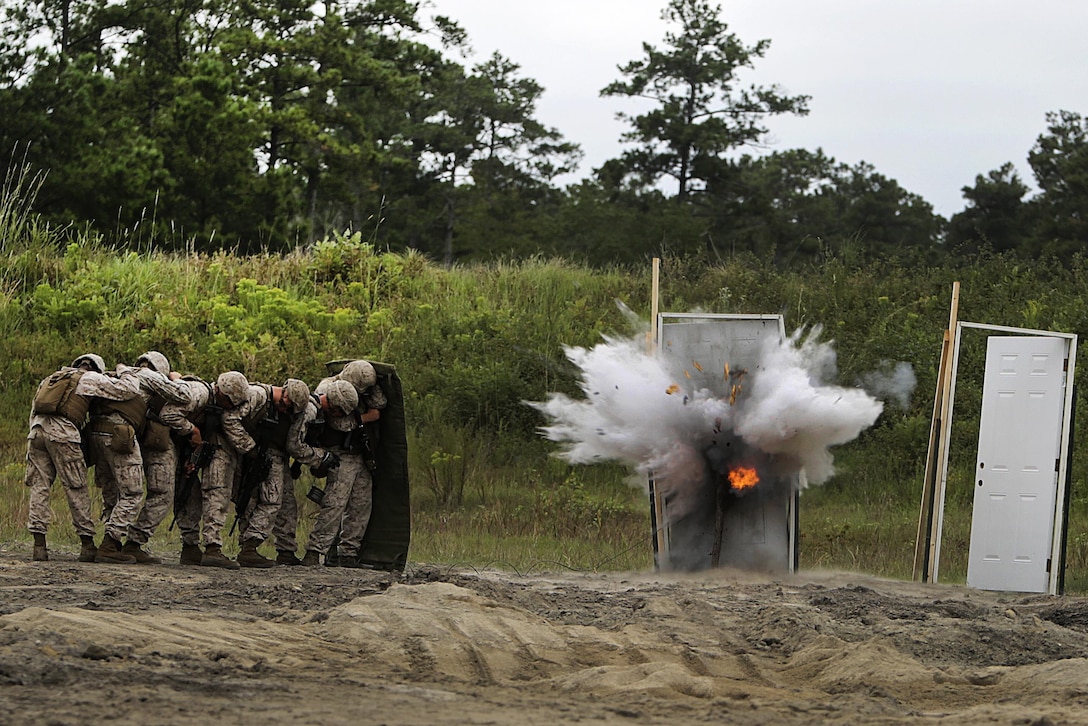 Marines take cover behind a shielding blanket as a water charge detonates during a demolitions exercise on Camp Lejeune, N.C., Sept. 22, 2015. U.S. Marine Corps photo by Cpl. Alexander Mitchell