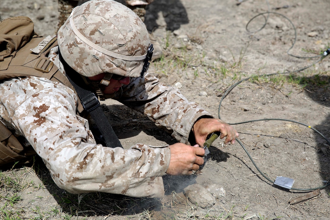 A Marine lies in the prone position while he pulls the timed fuse on a Bangalore charge to destroy a wire obstacle during a demolitions exercise on Camp Lejeune, N.C., Sept. 22, 2015. U.S. Marine Corps photo by Cpl. Alexander Mitchell