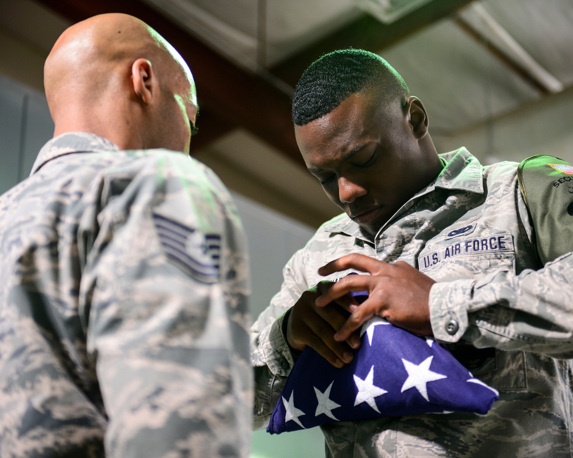 U.S. Air Force Staff Sgt. Assad Pharr, 386th Expeditionary Security Forces honor guardsman, folds the American flag during a battle cross memorial dedication at an undisclosed location in Southwest Asia, Sept. 28, 2015. By displaying the flag and giving it a distinctive fold, we show respect to the flag and express our gratitude to those individuals who fought and continue to fight for freedom, at home and abroad. (U.S. Air Force photo by Senior Airman Racheal E. Watson/Released) 