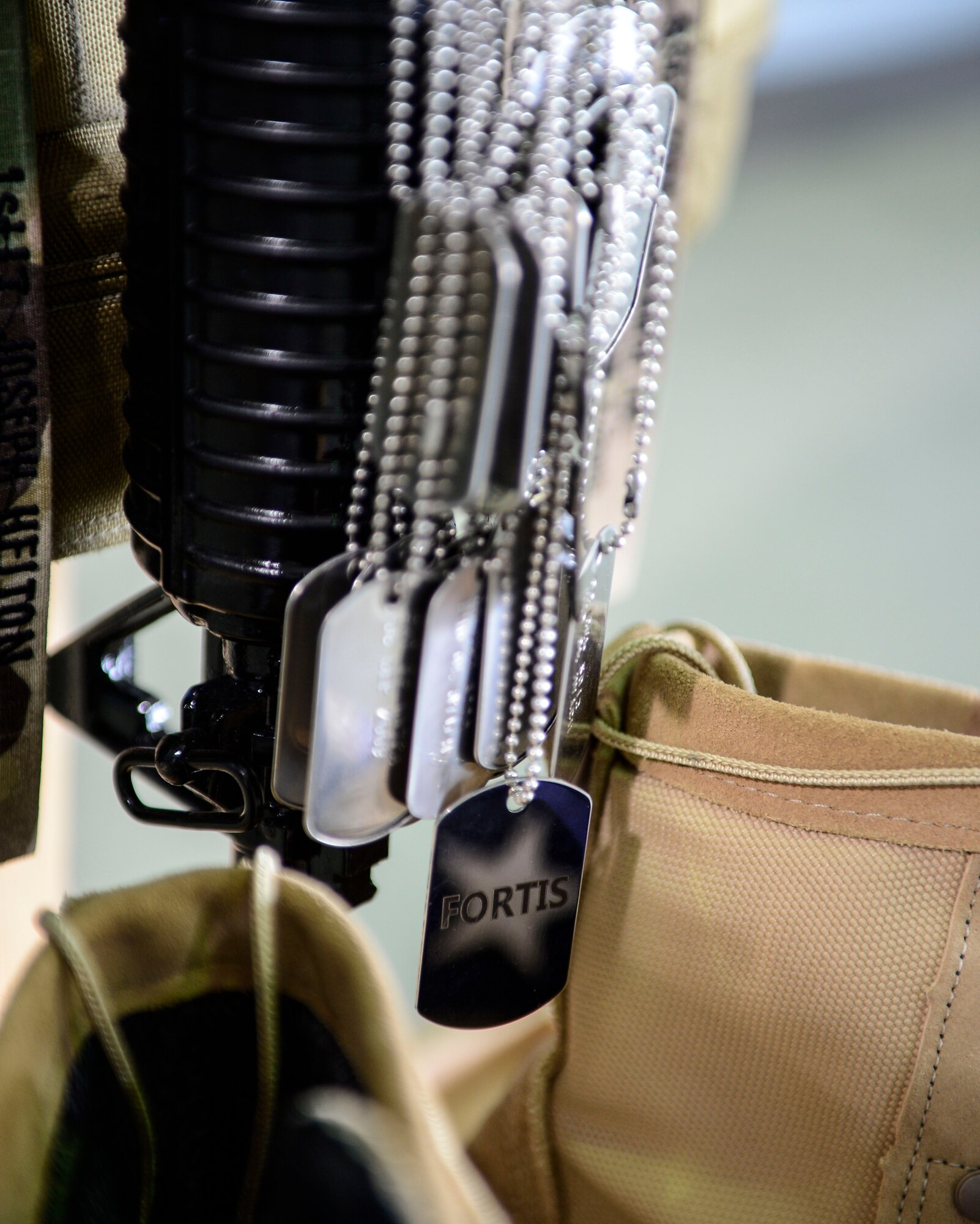 Dog tags of fallen security forces defenders hang on a battle cross during a memorial dedication at an undisclosed location in Southwest Asia, Sept. 28, 2015. The cross is a symbolic representation on the battlefield, or at the base camp, to show honor and respect for the dead. (U.S. Air Force photo by Senior Airman Racheal E. Watson/Released) 