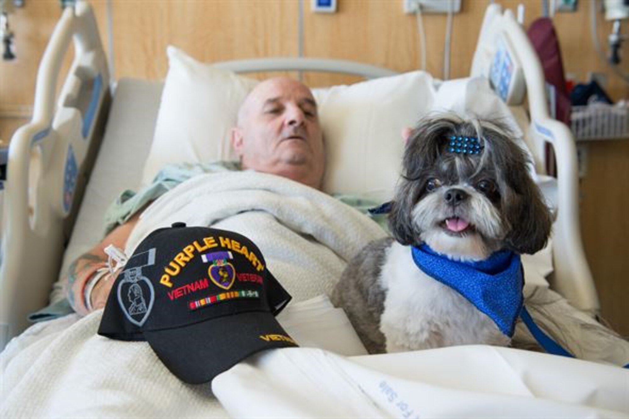 Toby, People Utilizing Pet Services program therapy dog, visits with Douglas Haas, Surgical Inpatient Unit patient, during the first PUPS program visit at the Keesler Medical Center Sept. 24, 2015, Keesler Air Force Base, Miss. The program allows dogs that are certified through the Delta Society, based in Gulfport, Miss., to visit patients at the medical center. 
