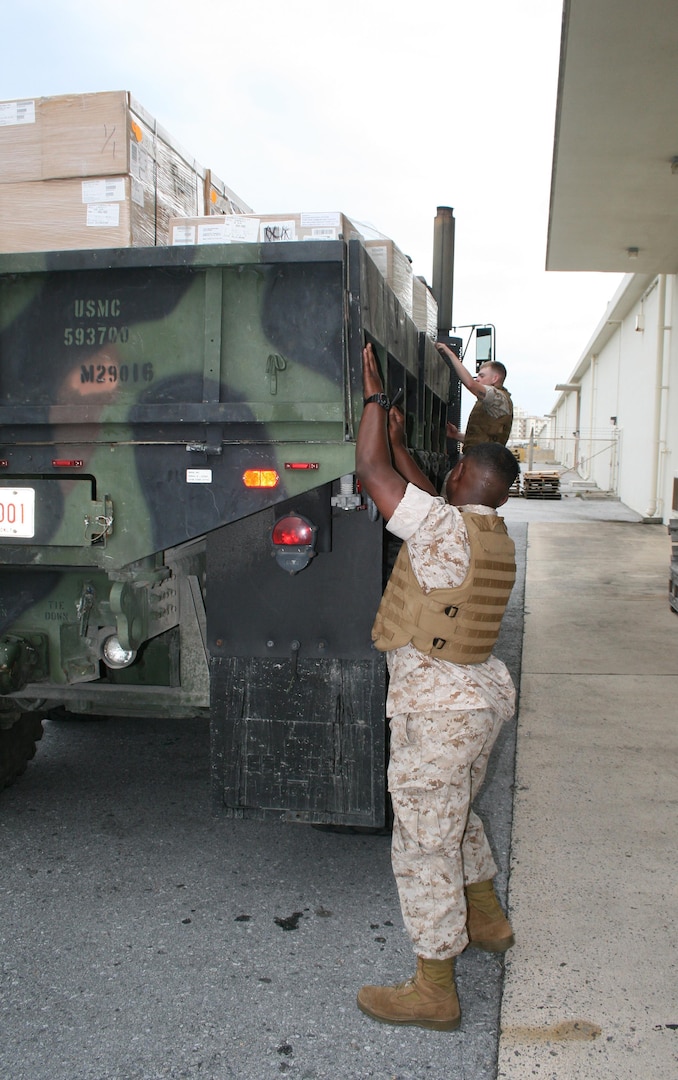 Marine Corps customers drop the sides of a truck so materiel can be unloaded. The Marines are customers of DLA Distribution Yokosuka, Japan, at Okinawa.