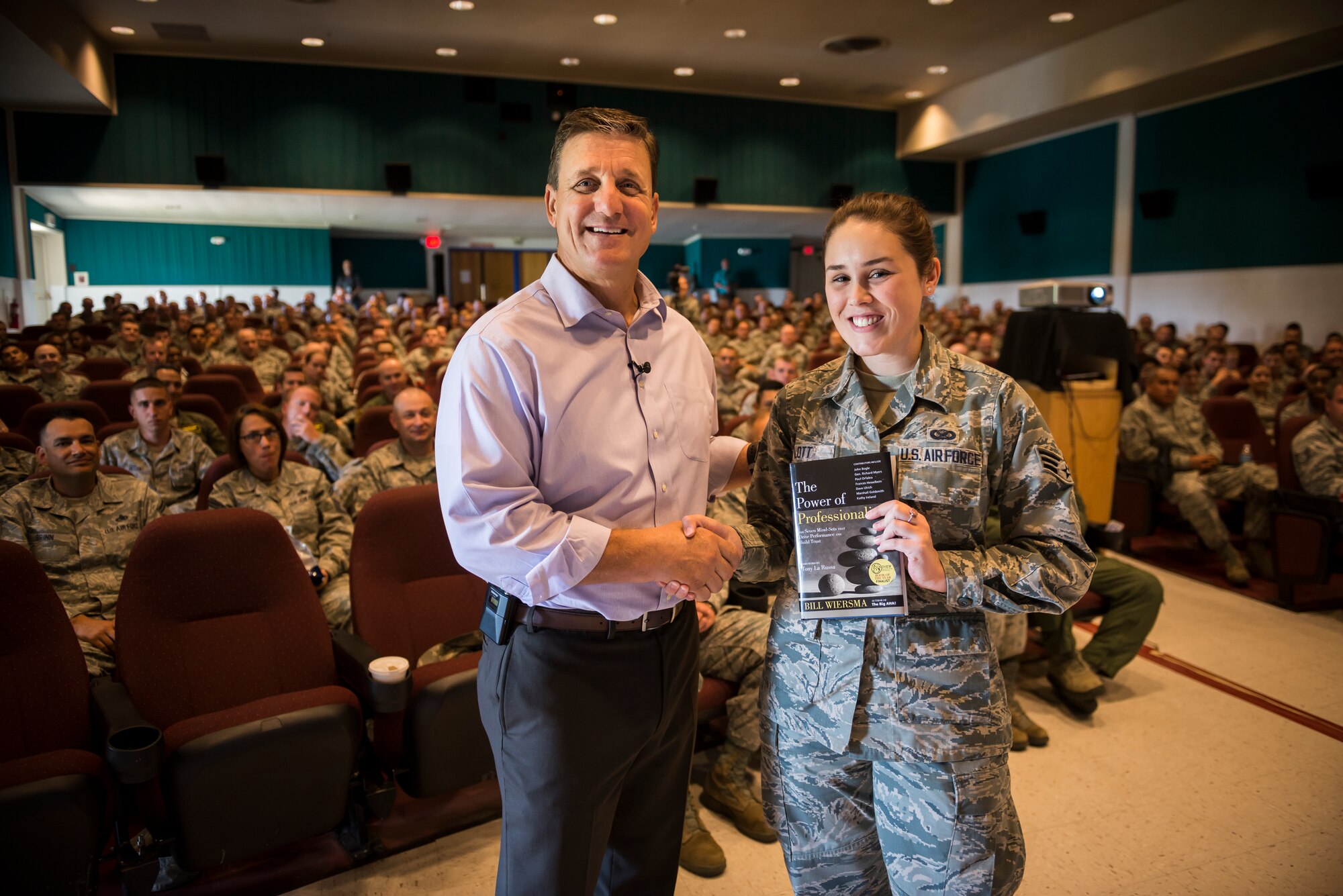 Dr. Jeffrey Smith (left), senior executive advisor from the U.S. Air Force Profession of Arms Center of Excellence, presents a copy of "The Power of Professionalism," by Bill Wiersma, to Senior Airman Malissa Lott, 366th Fighter Wing public affairs photojournalist, in the base theater at Mountain Home Air Force Base, Idaho, Sept. 29, 2015. Lott was selected at random from the audience attending Smith's "Professionalism: Enhancing Human Capital" seminar and was recognized as being the 10,000th student trained in that course. (U.S. Air Force photo/Tech. Sgt. Samuel Morse)